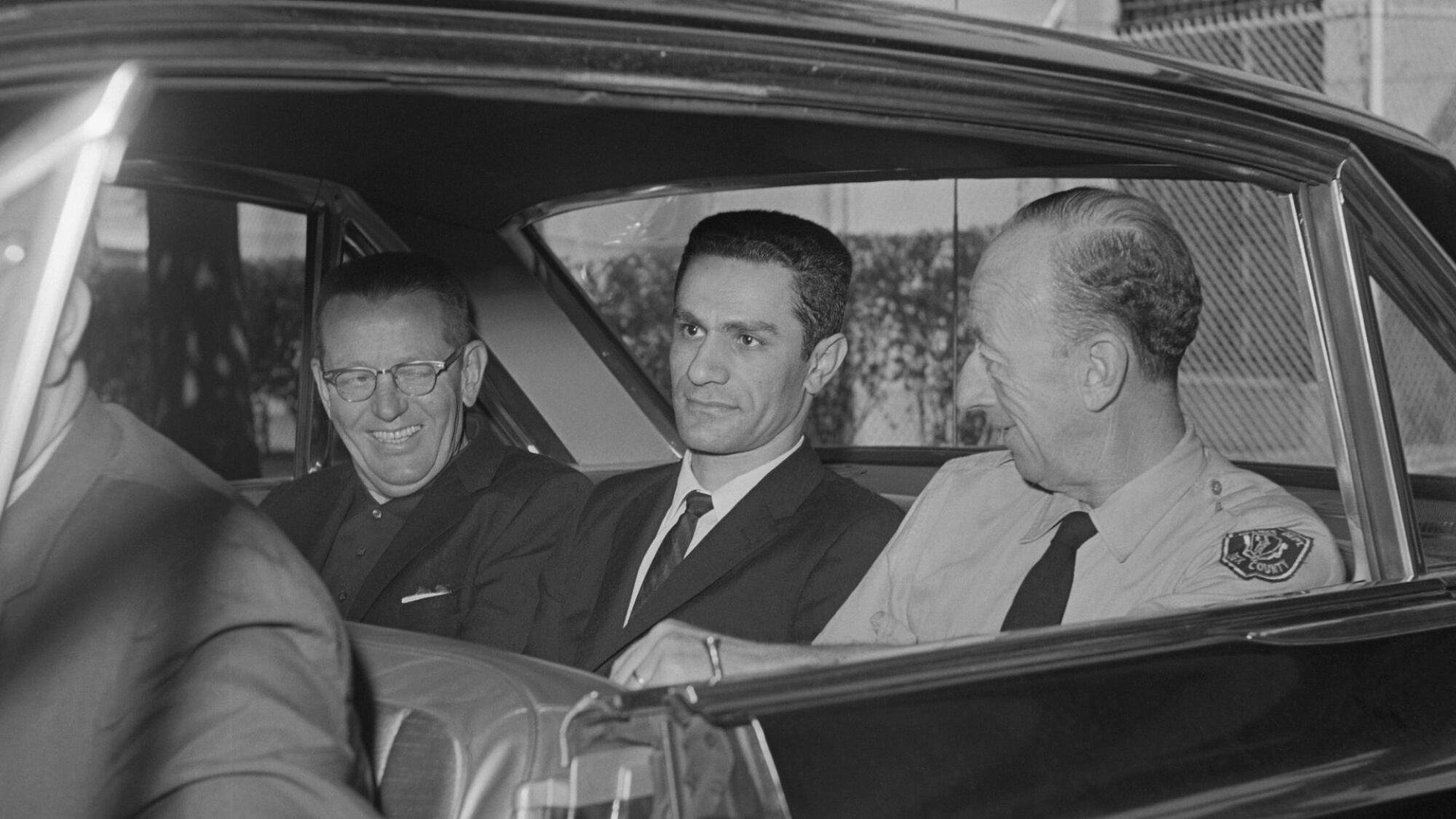 Le meurtrier reconnu coupable George Nassar (au centre) est assis dans une voiture entre deux responsables de l'application des lois alors qu'il attend d'être transporté de la prison de Salem à la prison d'État de Walpole.
