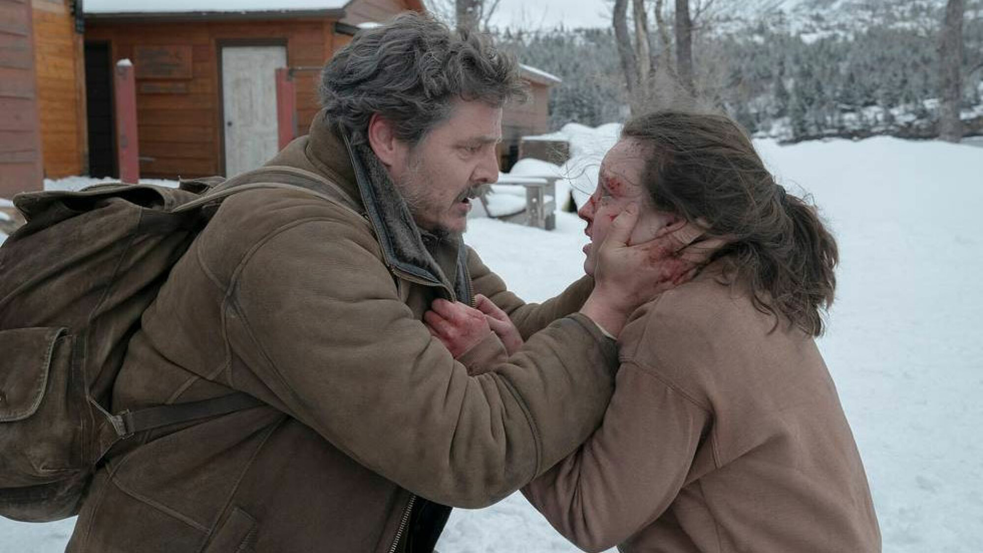 Un homme dehors dans la neige berce le visage d'une jeune fille blessée.