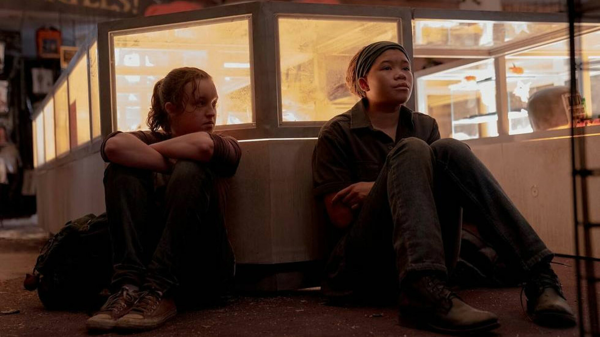 Deux jeunes filles s'assoient l'une à côté de l'autre, le dos contre un mur.