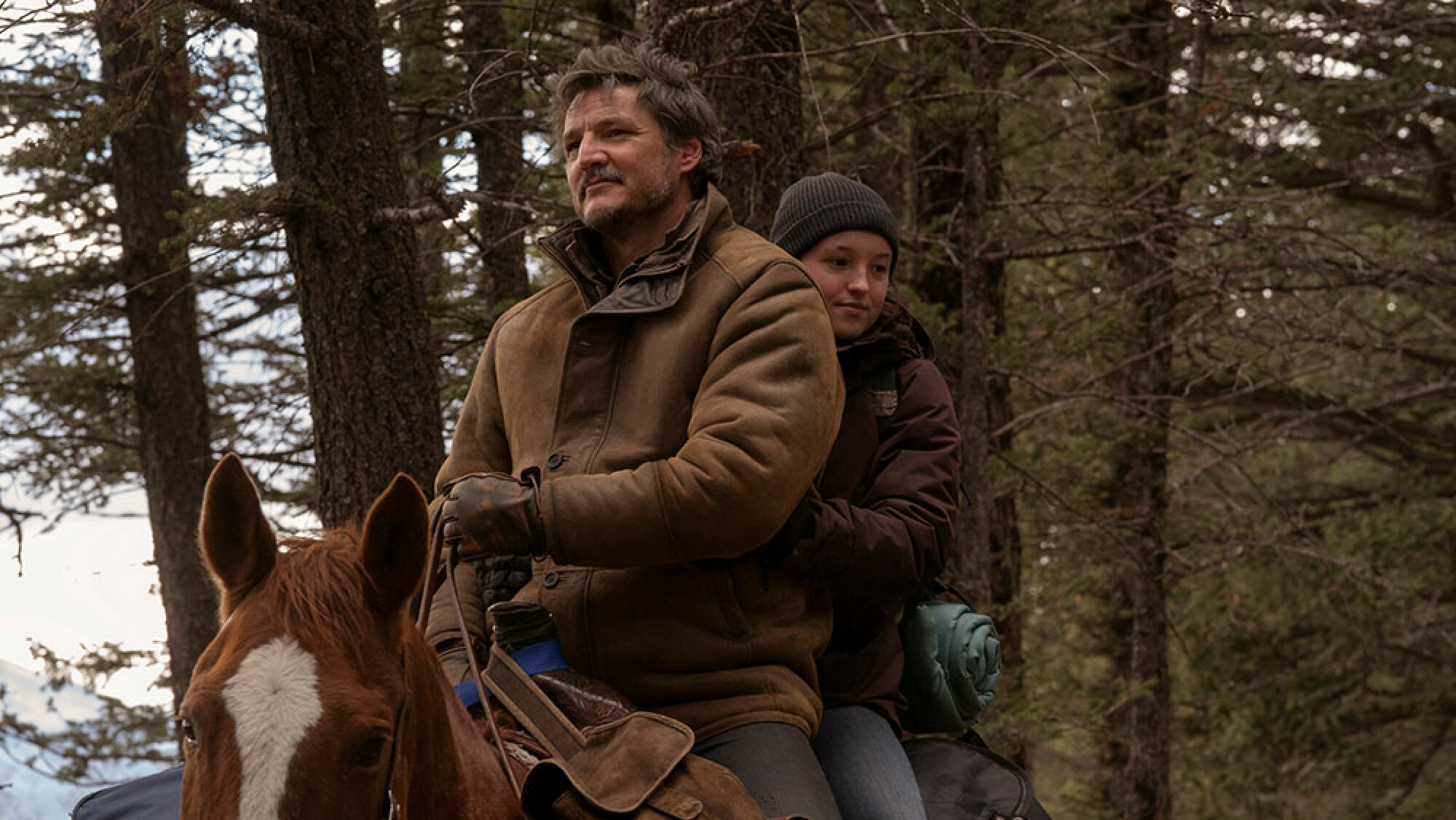 Un homme et une jeune fille traversent la neige à cheval.