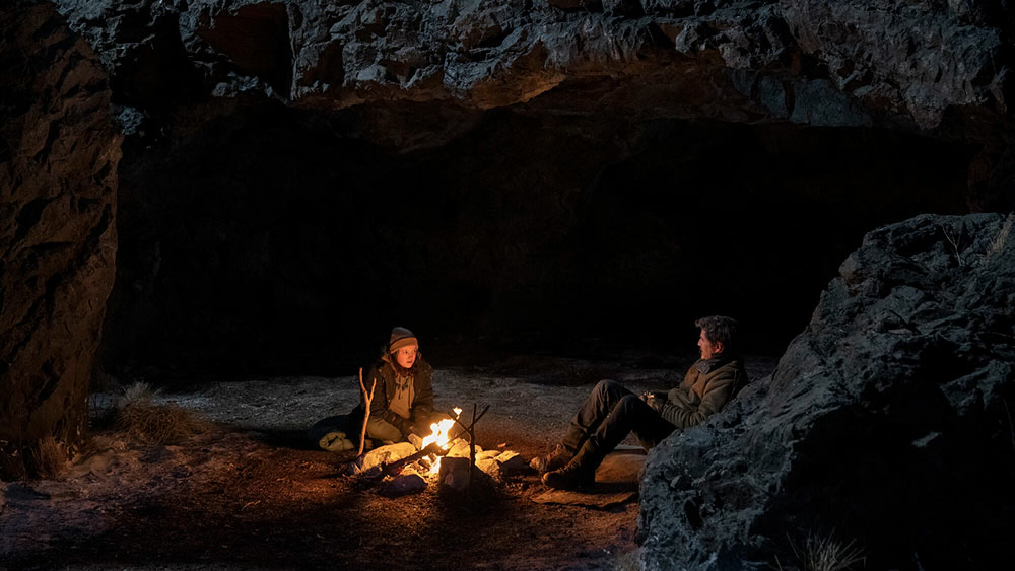 Un homme et une jeune fille sont assis à l'extérieur la nuit près d'un feu de camp.