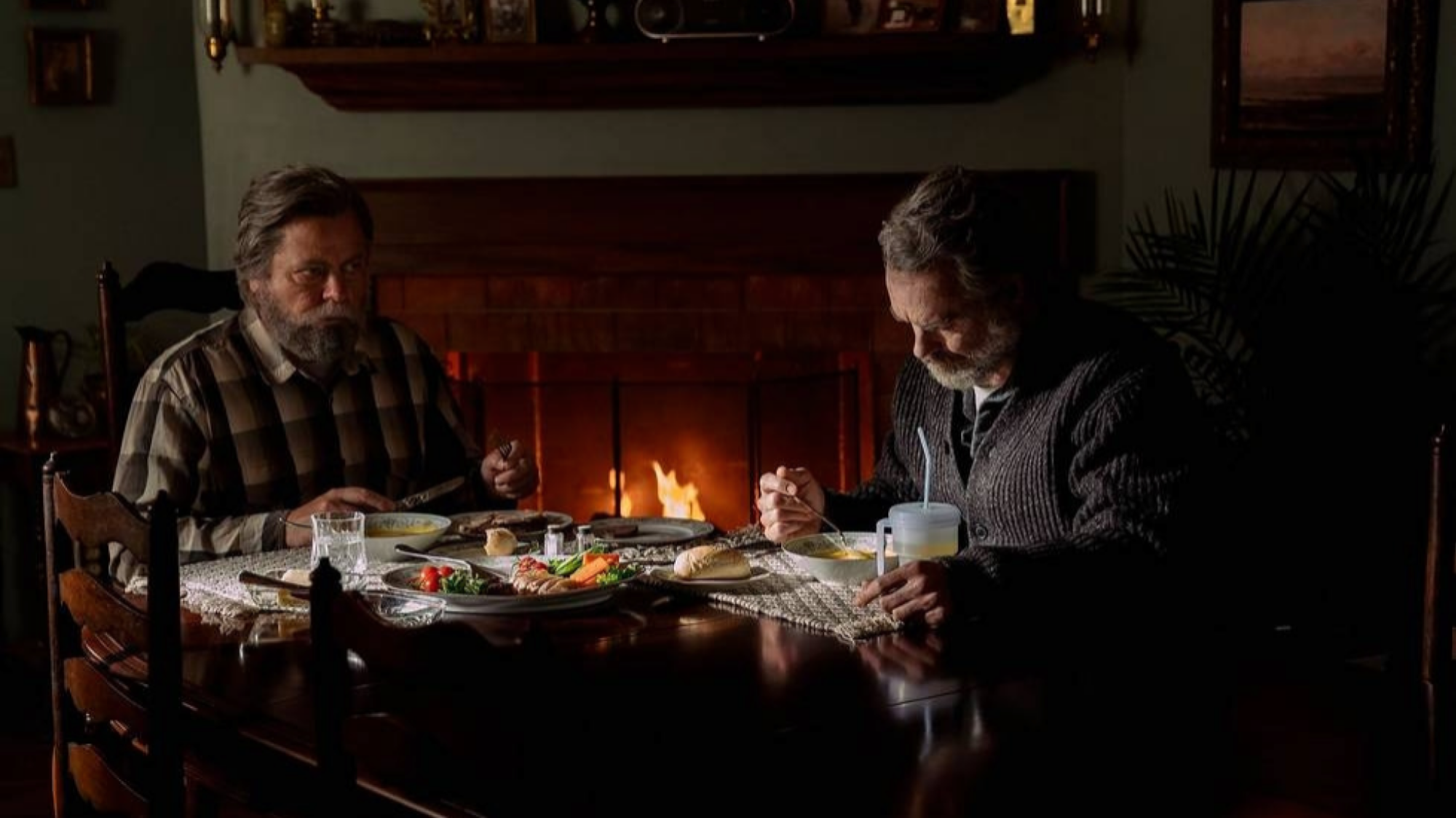 Deux hommes dînent près d'une cheminée. 