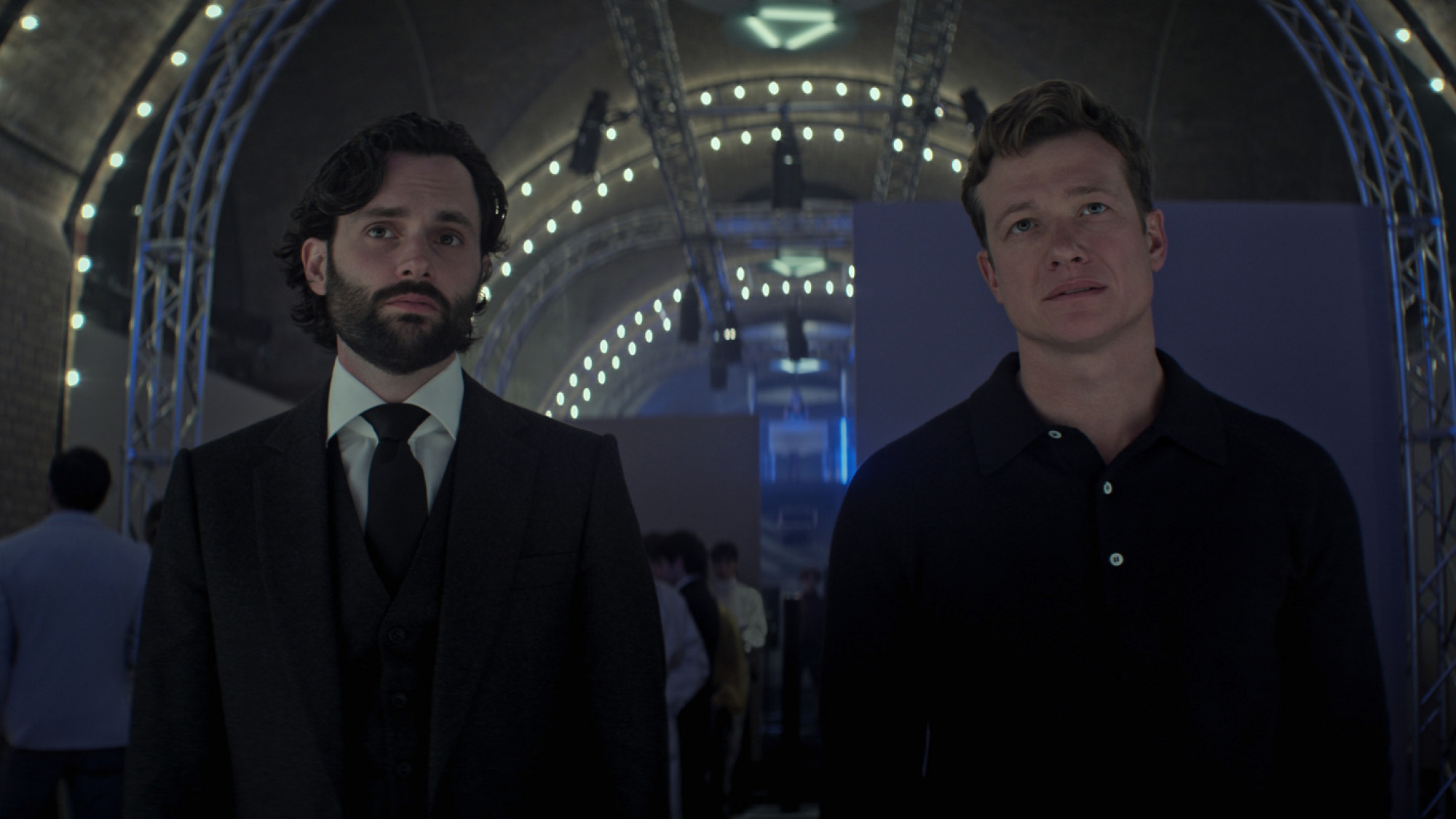 Deux hommes en costume se tiennent dans un musée futuriste. 