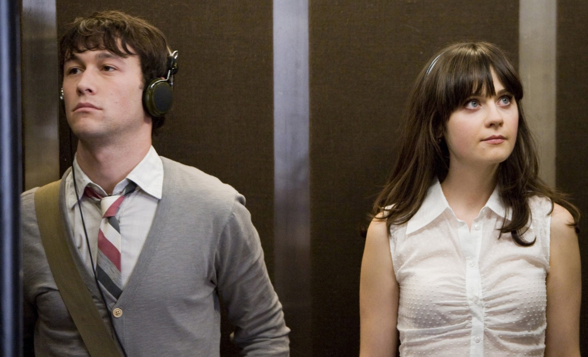 Un homme et une femme debout dans un ascenseur et regardant loin l'un de l'autre ;  Joseph Gordon-Levitt et Zoeey Deschanel dans 