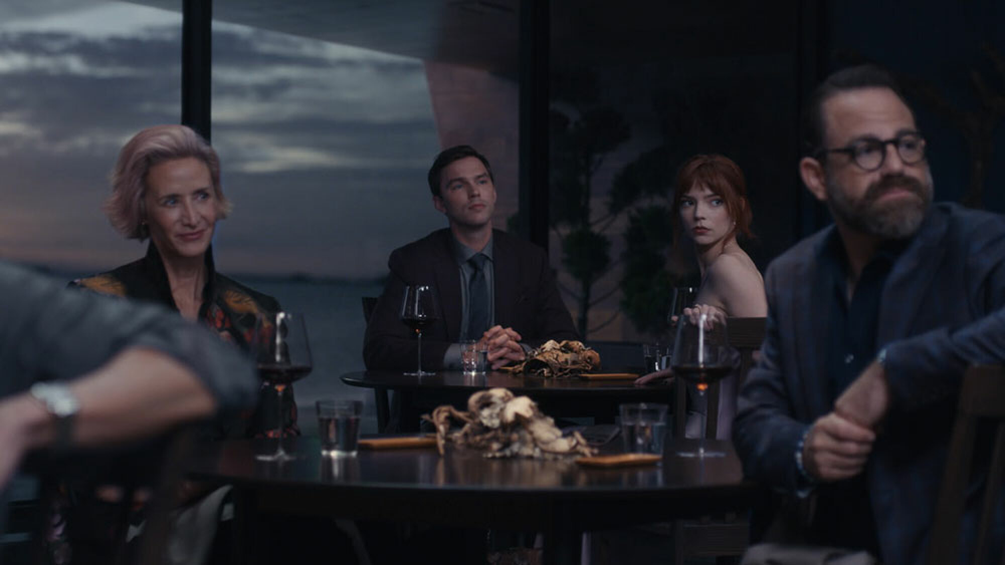 Un groupe d'invités bien habillés est assis dans un restaurant avec vue sur l'océan.