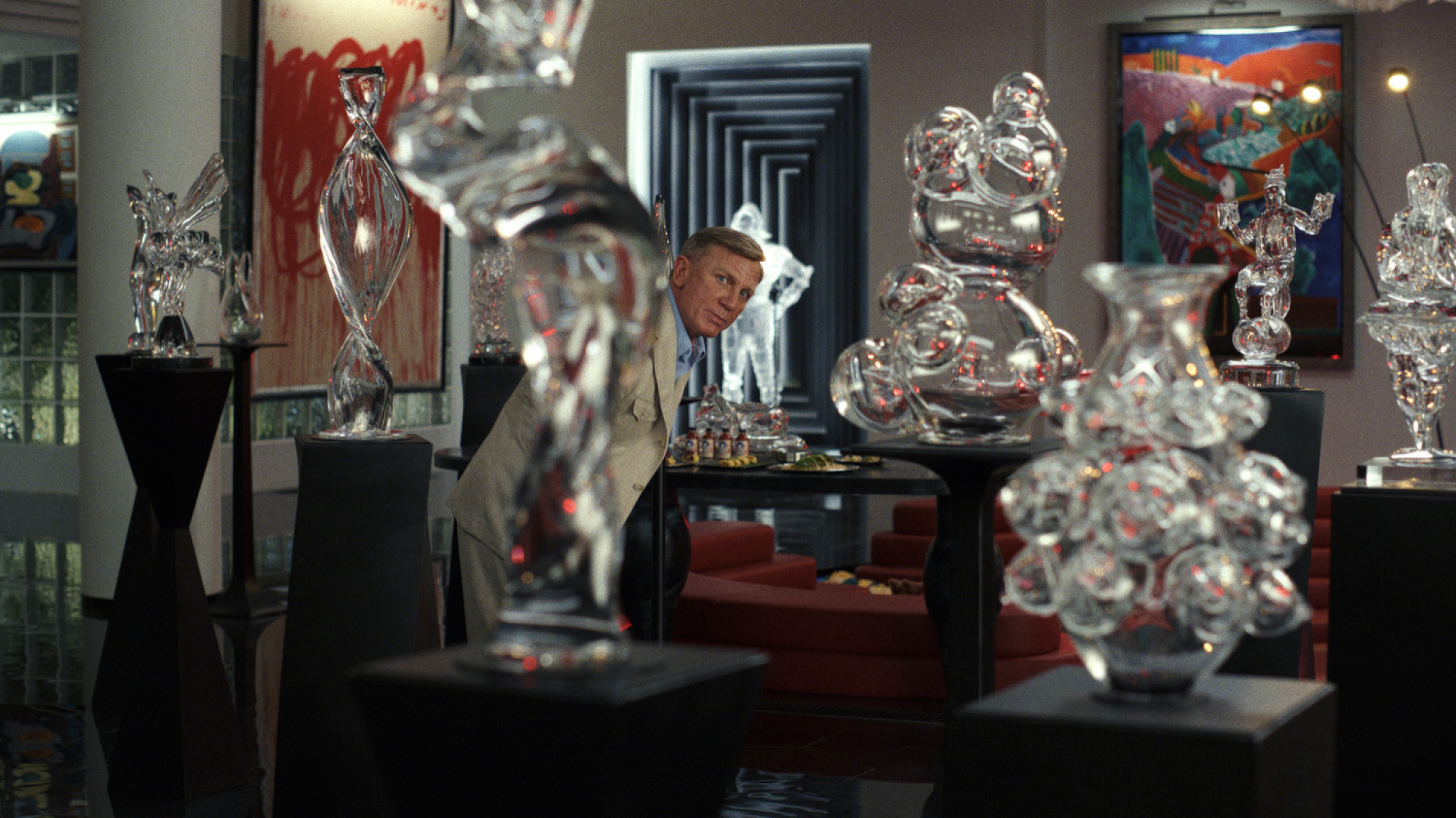 Un homme en costume se tient dans une pièce remplie de statues de verre. 