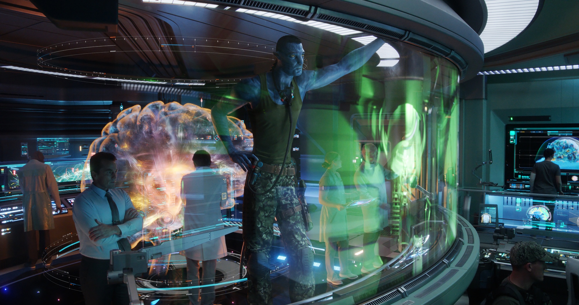 Un extraterrestre Na'vi bleu se tient avec des scientifiques humains dans un grand laboratoire.