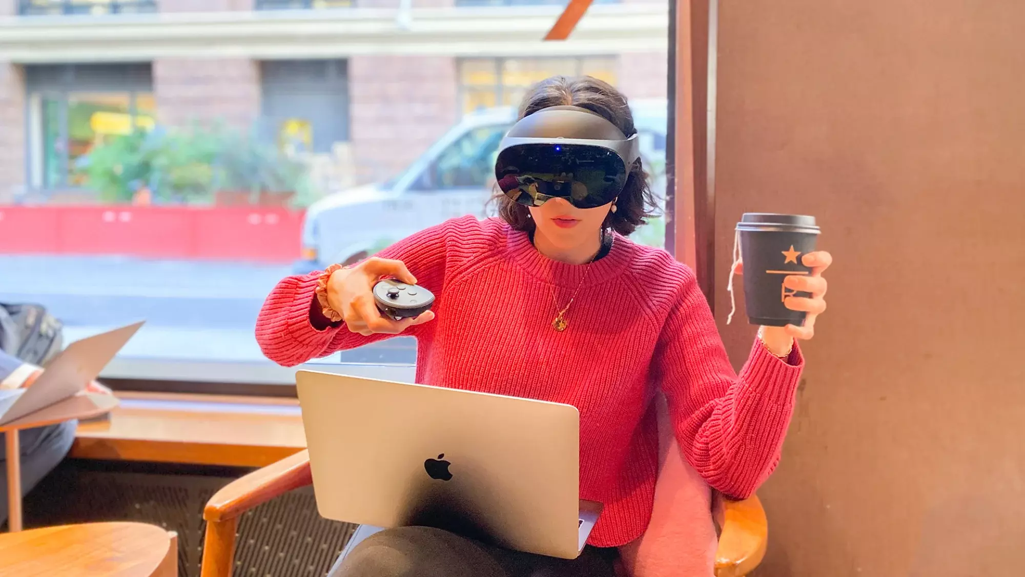 Utilisateur de Meta Quest Pro portant un casque à l'intérieur de Starbucks avec un ordinateur portable sur les genoux