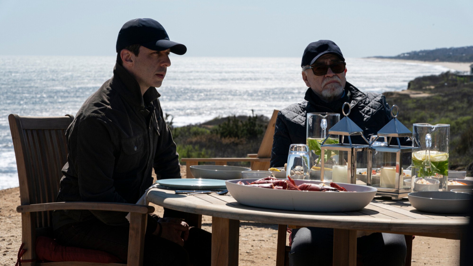 Deux hommes déjeunent près de la mer. 