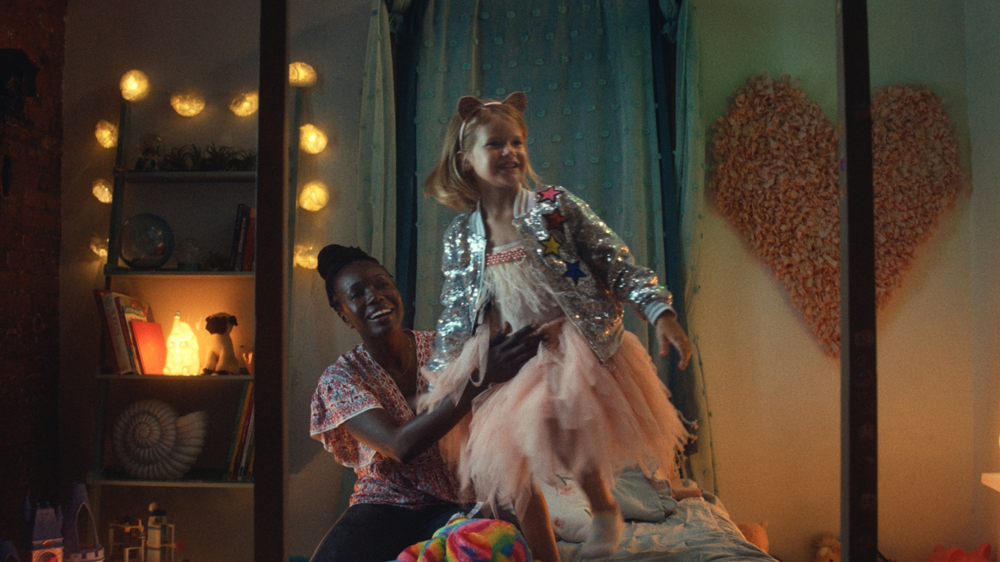Une femme noire excitée tient une jeune fille blanche alors qu'elle saute joyeusement sur le lit