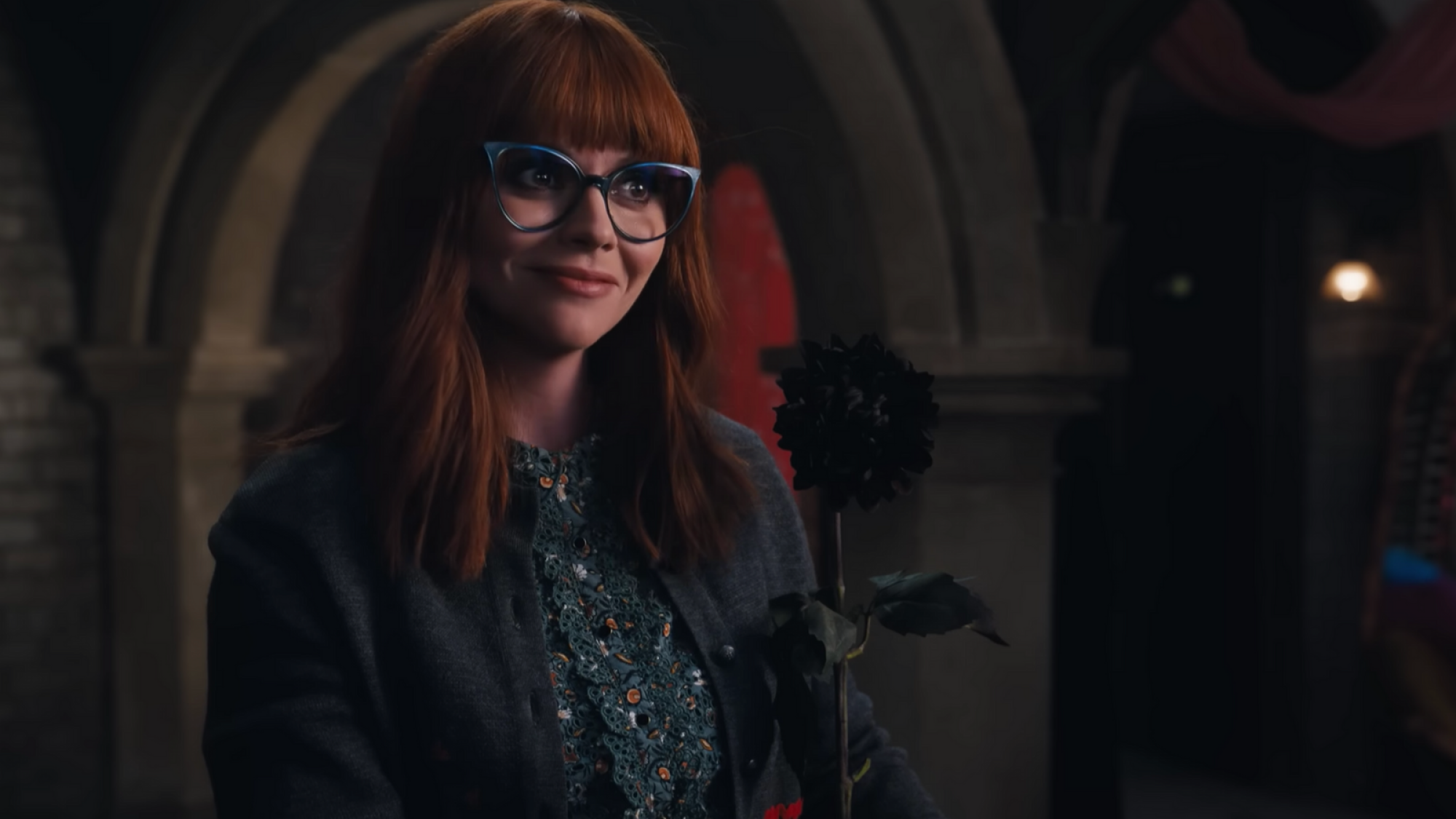 Une femme aux yeux impatients tient une fleur noire. 