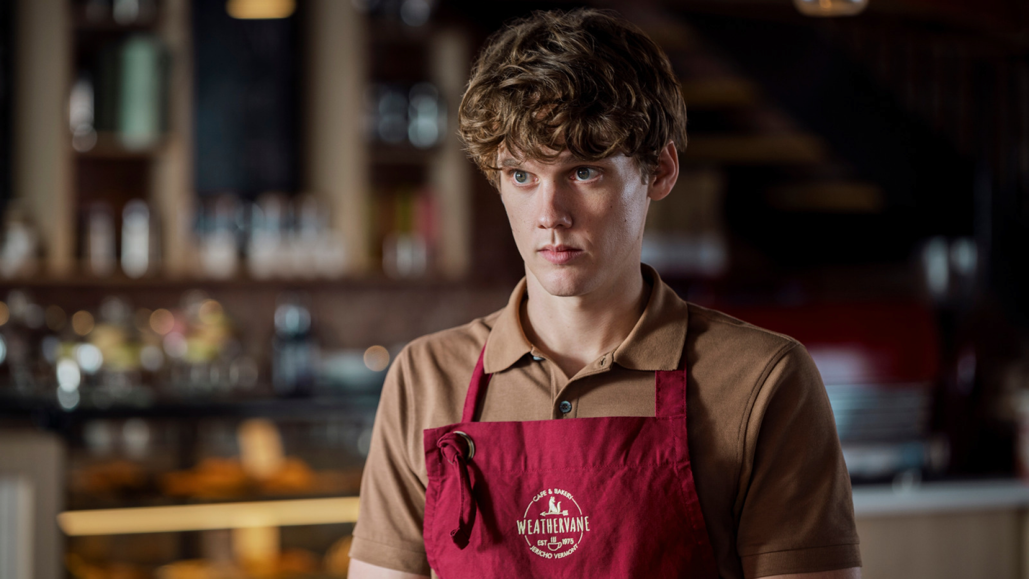 Barista dans un tablier se tient derrière un comptoir.