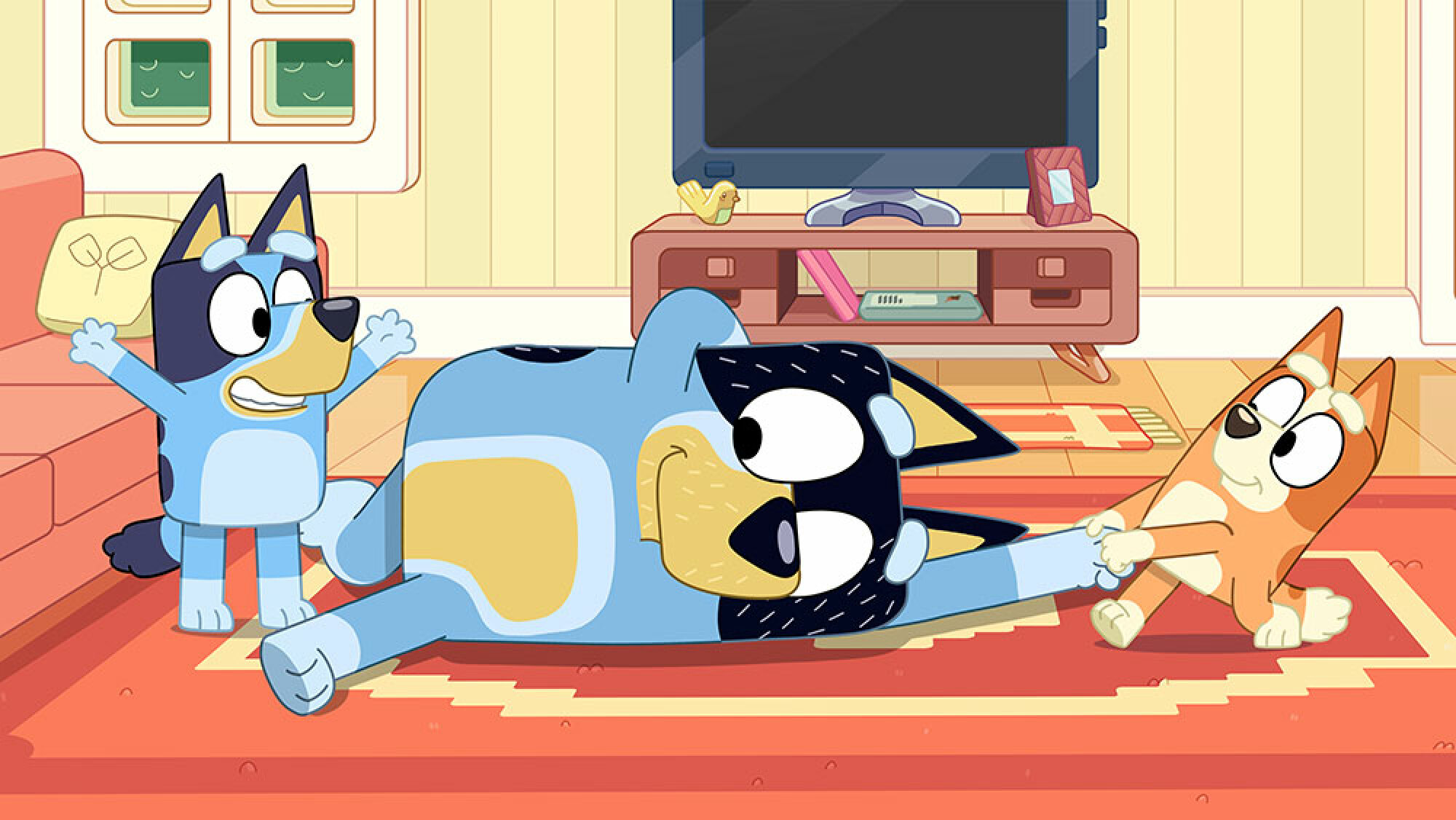 Un chien de dessin animé est allongé sur le tapis en souriant tandis que deux petits chiens jouent avec lui.