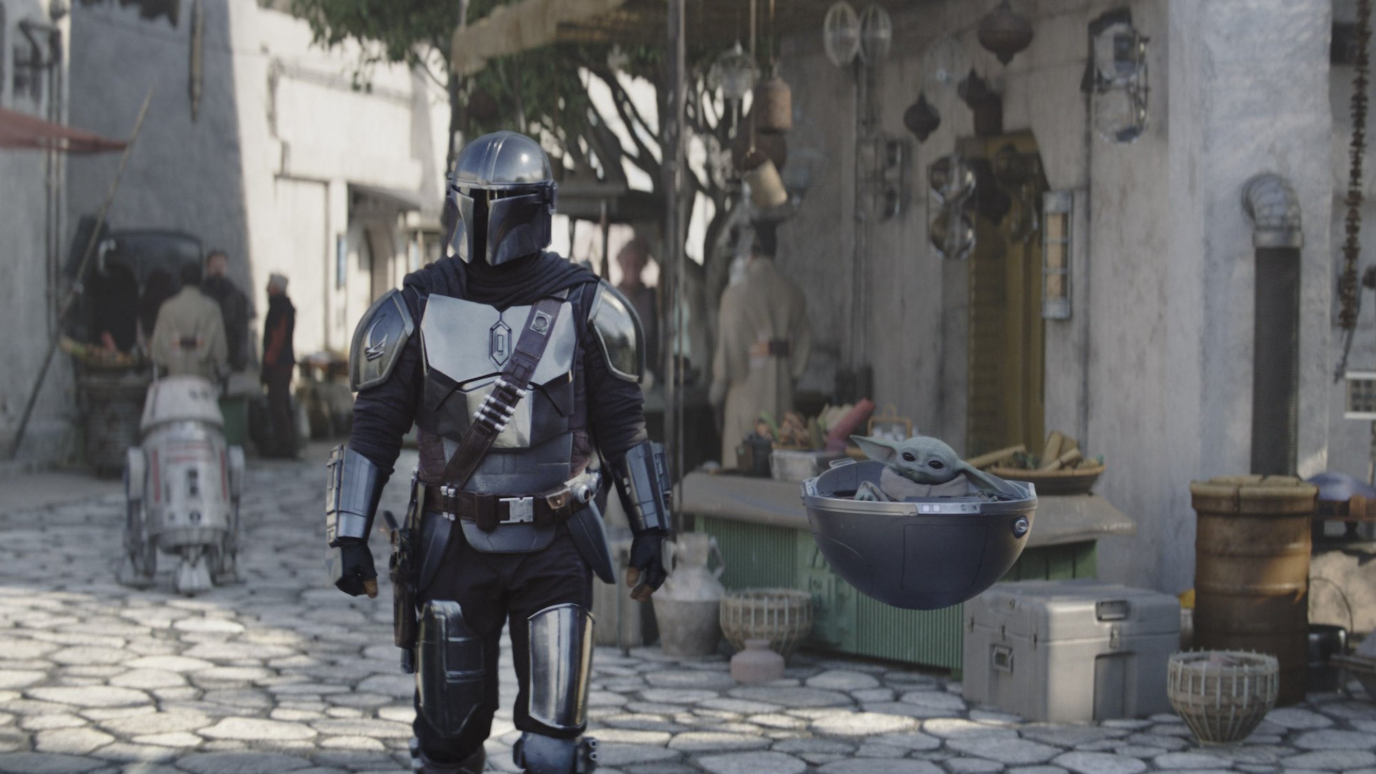 Un guerrier en armure d'argent et casque se promène dans une ville à côté d'une petite créature verte dans un landau orbe.