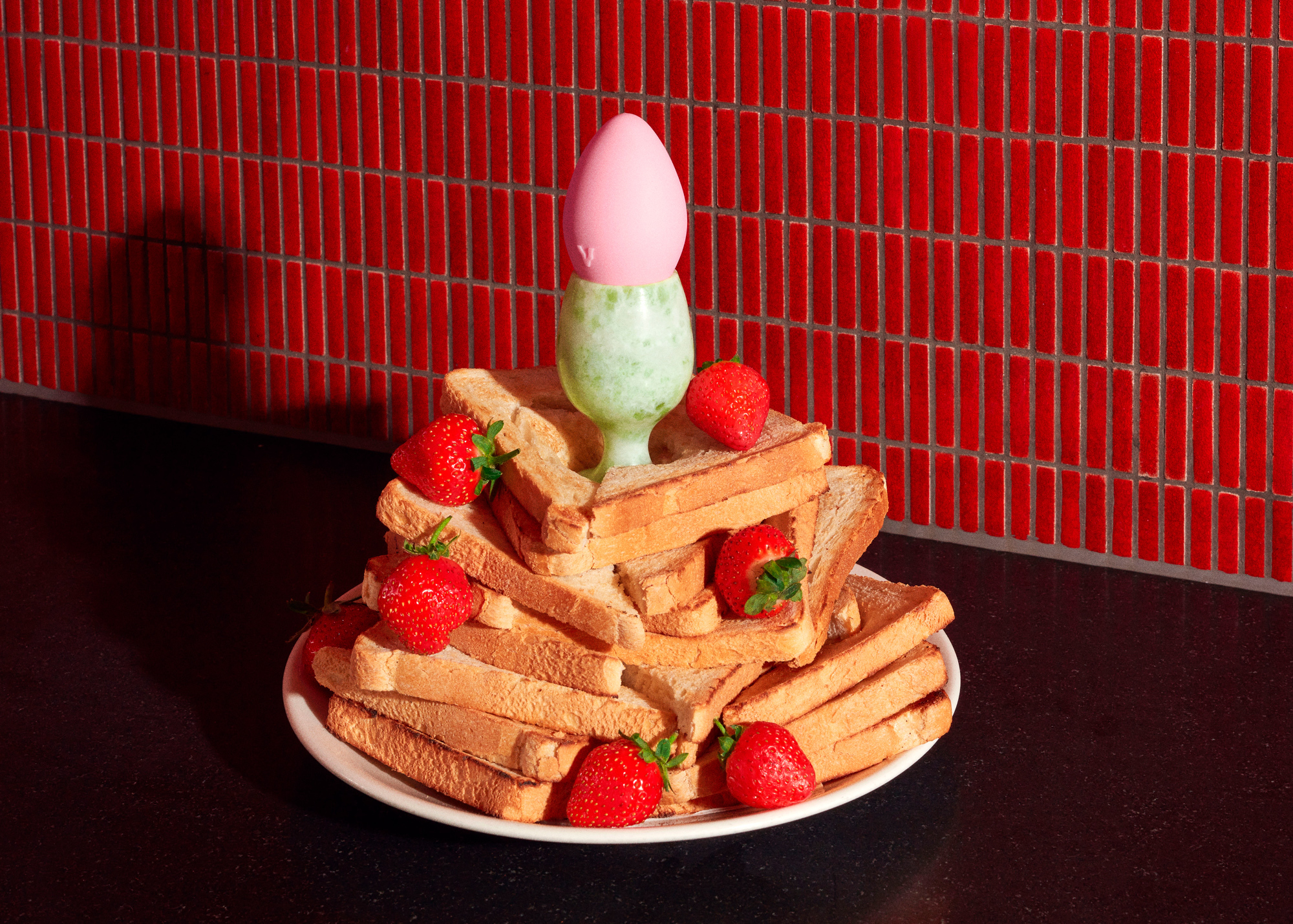 Un petit vibromasseur se pose sur une assiette de pain grillé et de fraises.