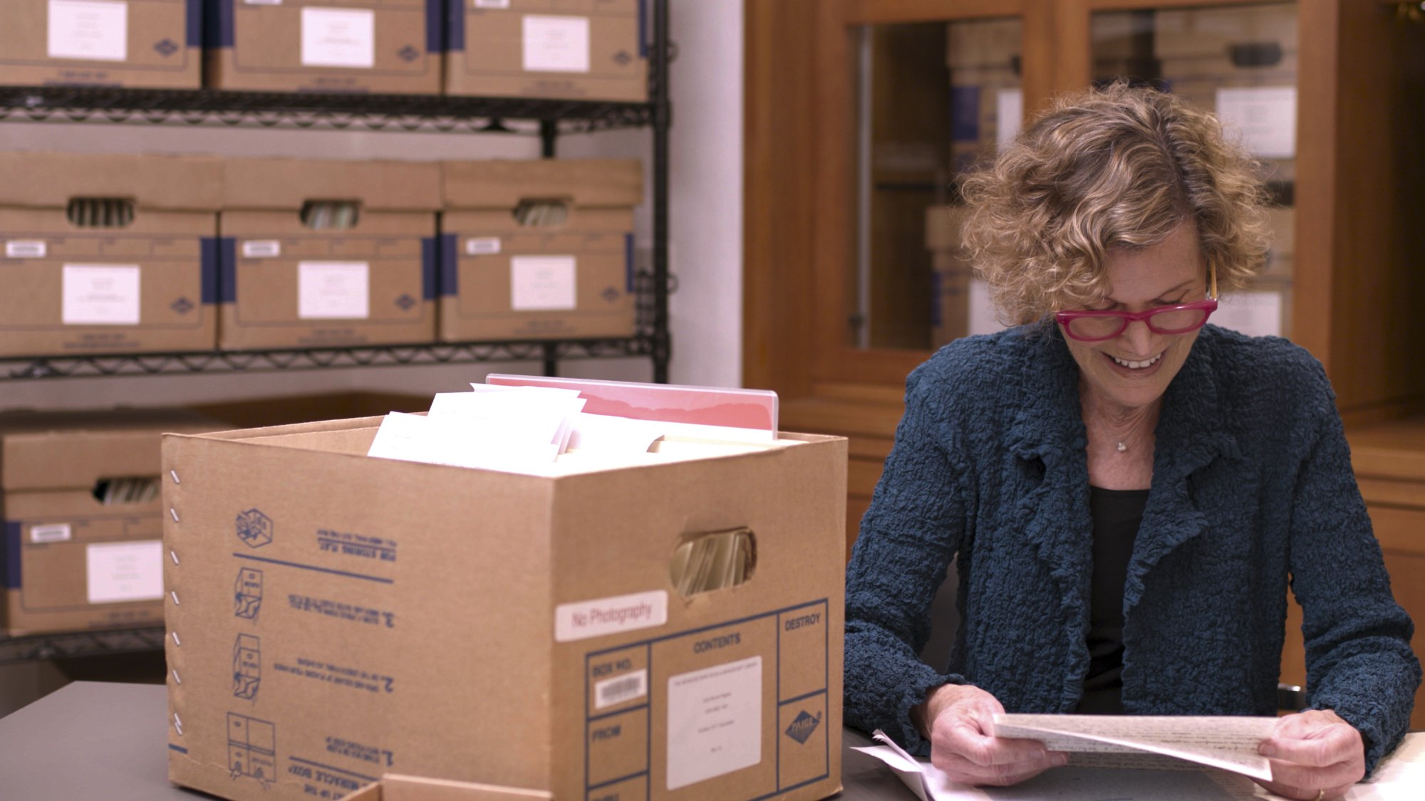 Judy Blume est assise dans une archive, regardant à travers une boîte en carton de ses lettres.