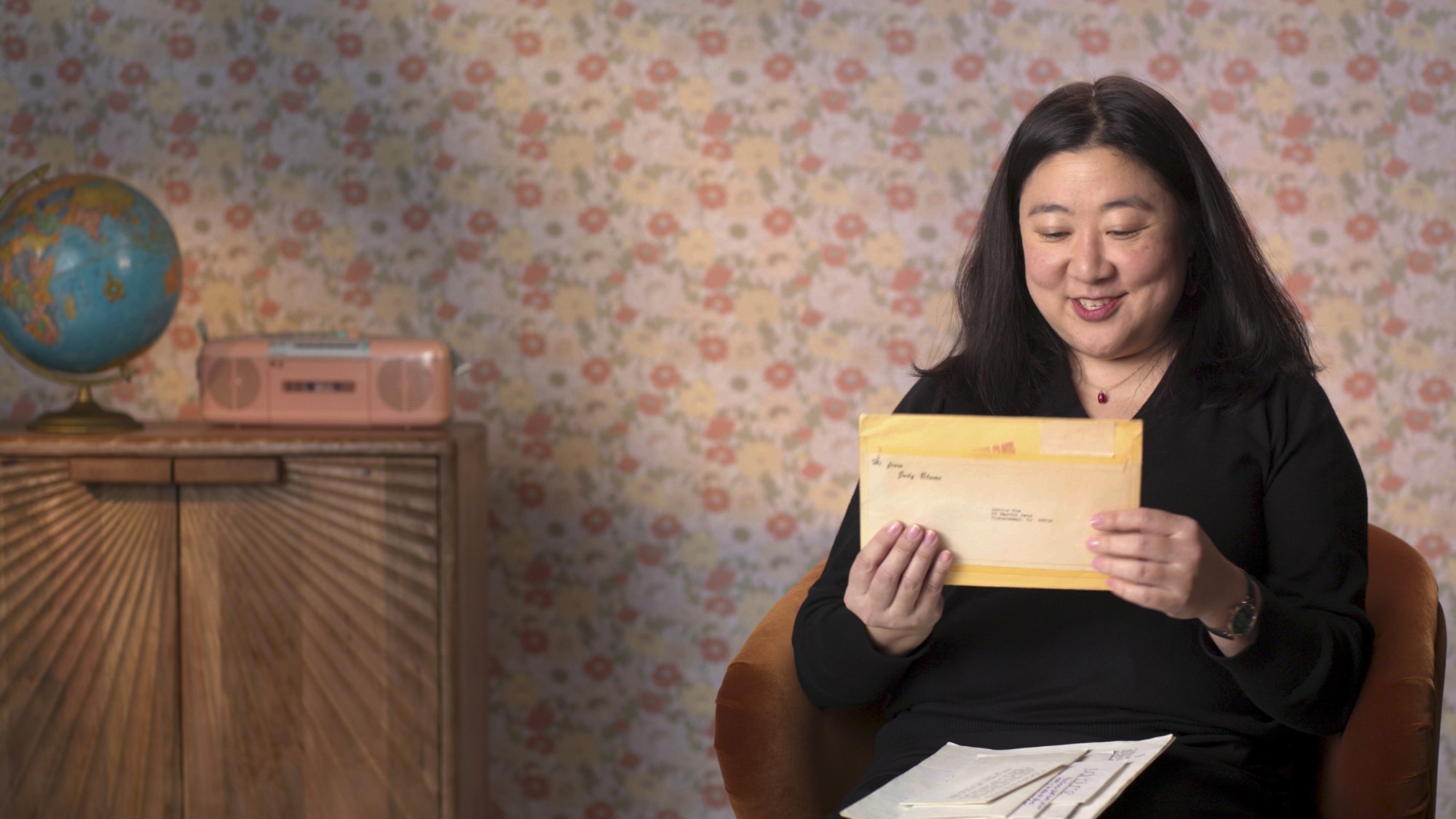 Lorrie Kim, une femme en blouse noire, tient une enveloppe.