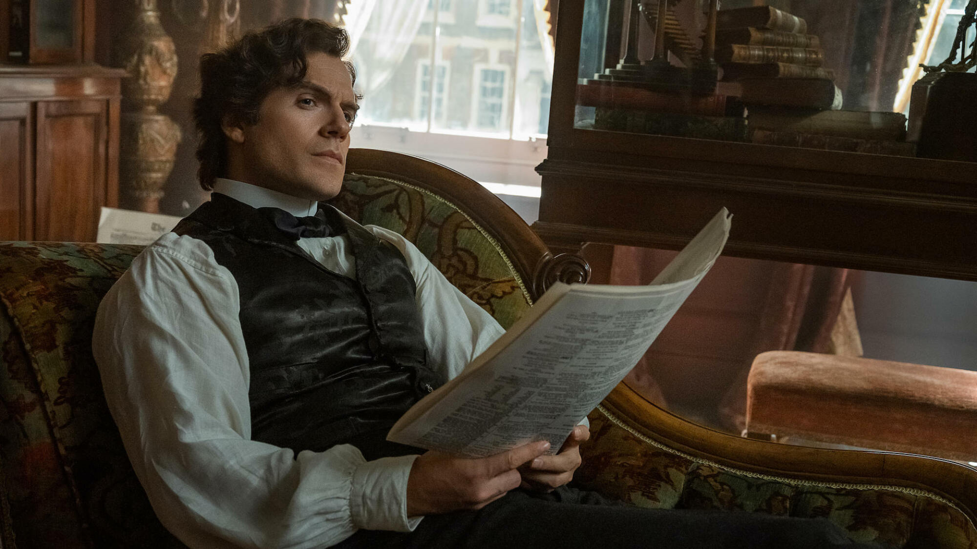 Un homme en gilet est allongé sur une chaise longue tenant un journal.