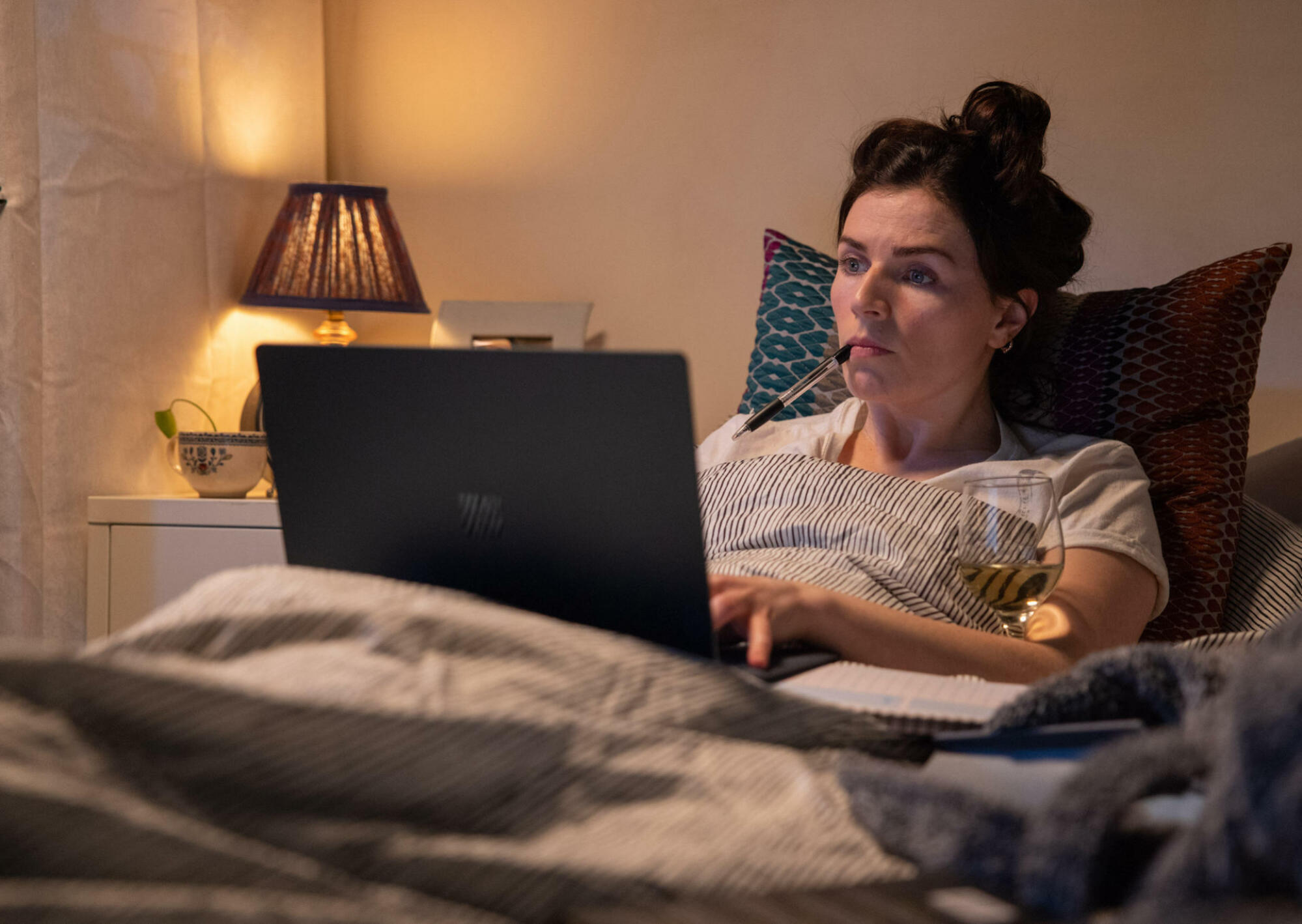 Une photo d'Aine (Aisling Bea) assise en mauvais état avec son ordinateur portable et un verre de vin dans 