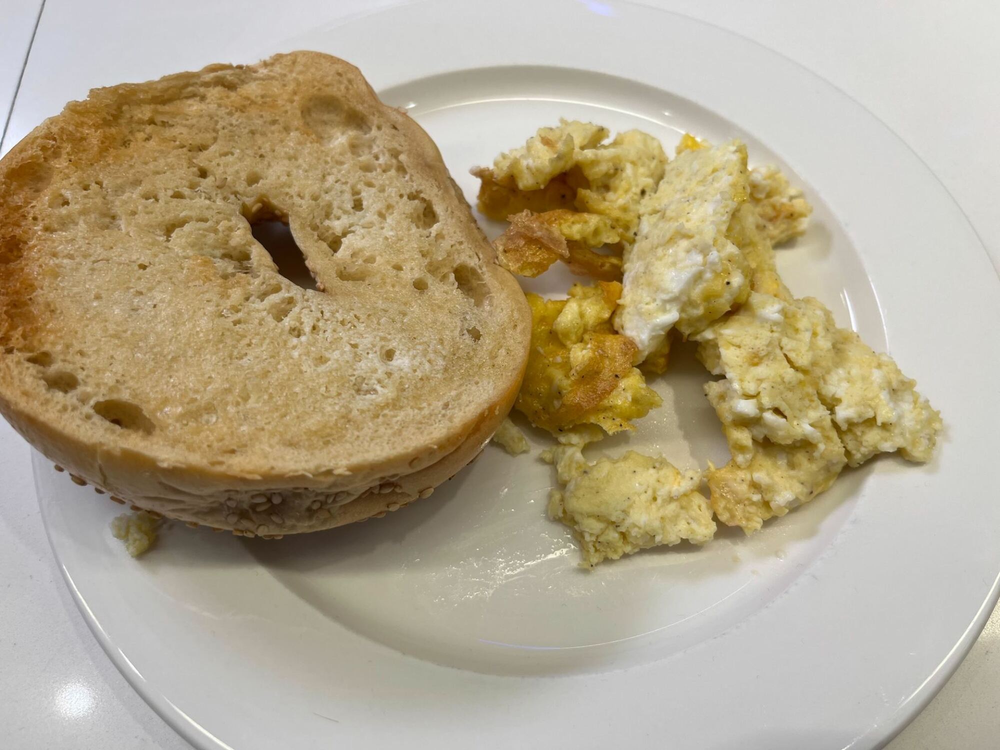 œufs trop cuits et bagel insuffisamment cuit sur assiette