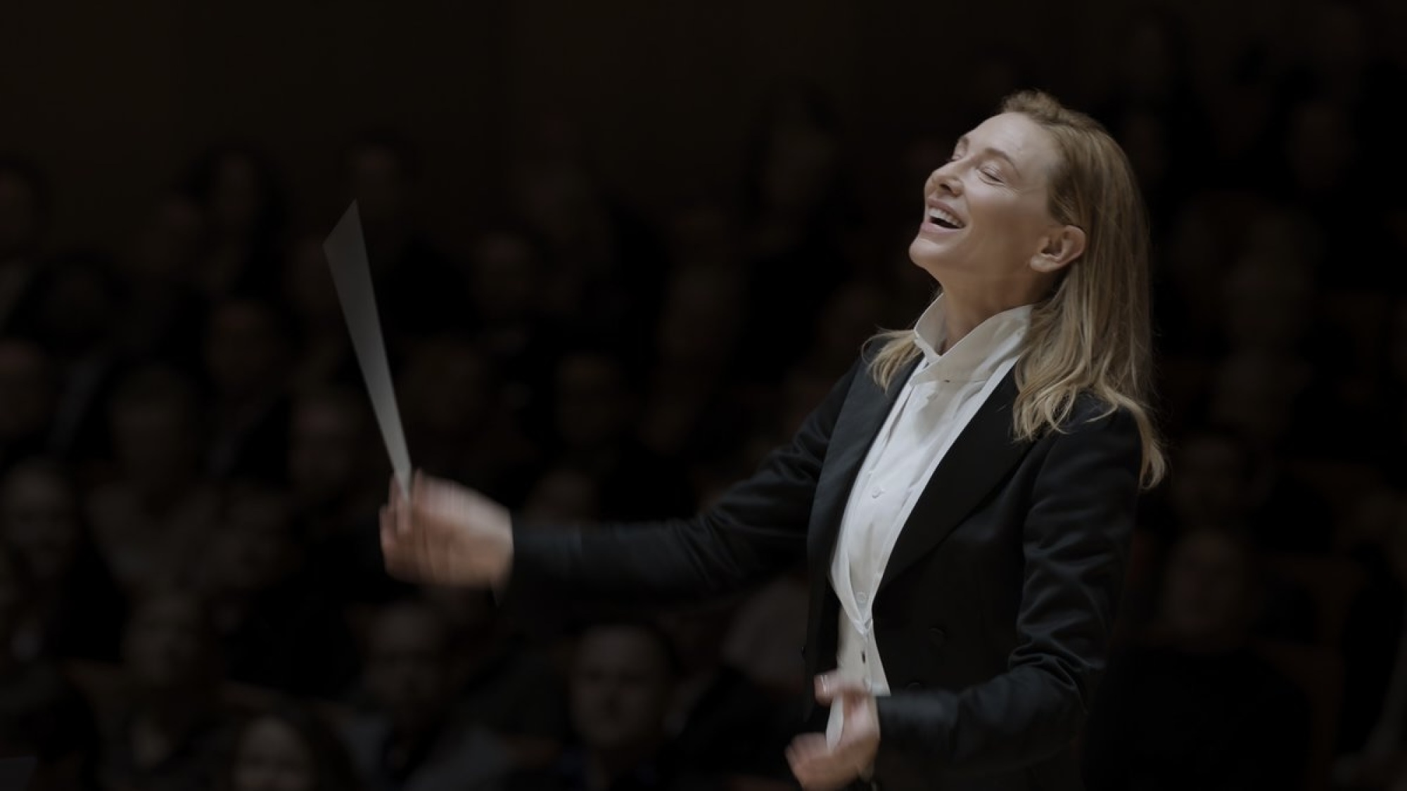 Une femme en costume dirige un orchestre.