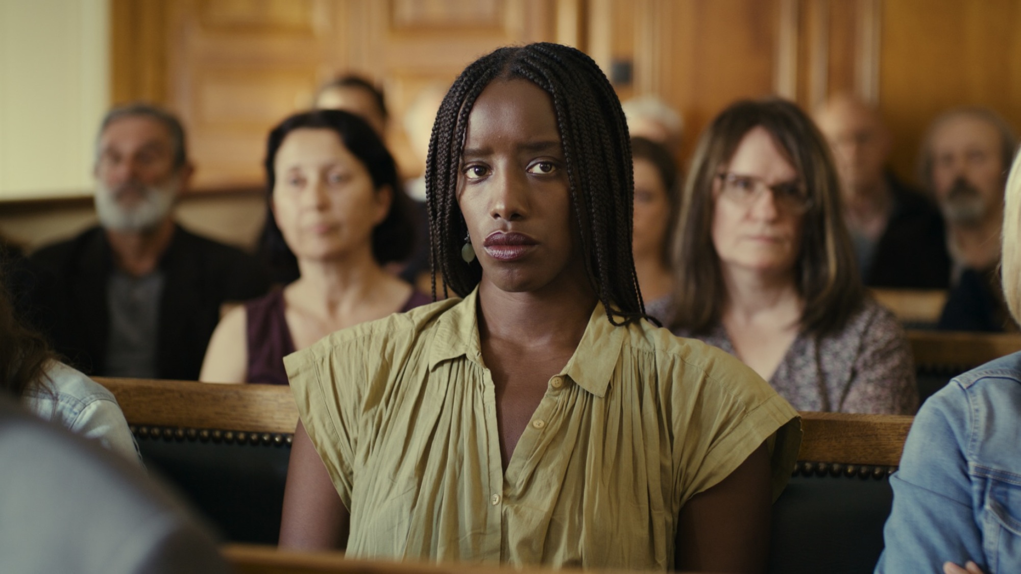 Une femme est assise dans la galerie d'une salle d'audience.