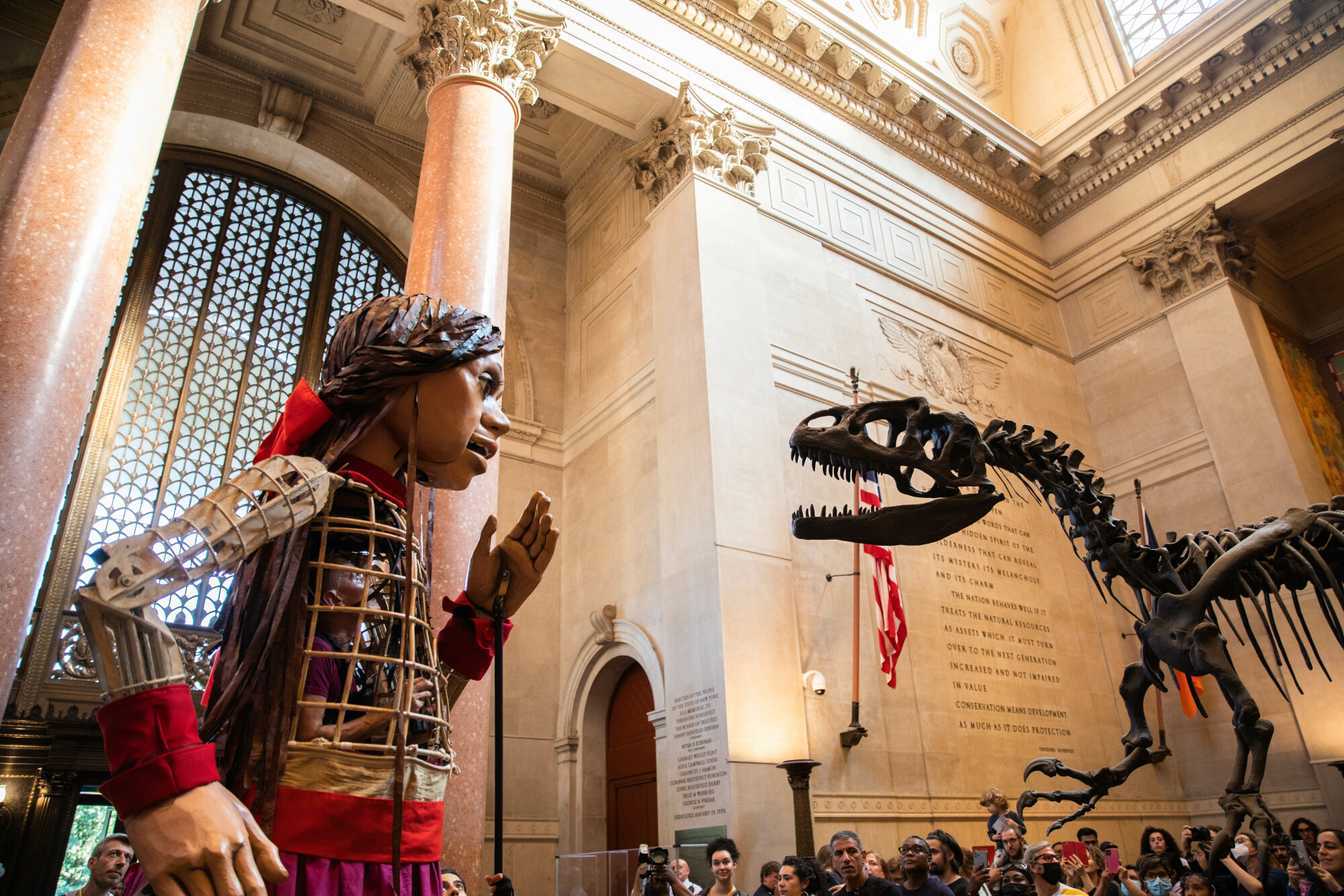 Amal se tient face à face avec un squelette de dinosaure fossilisé dans le hall principal du Musée américain d'histoire naturelle.