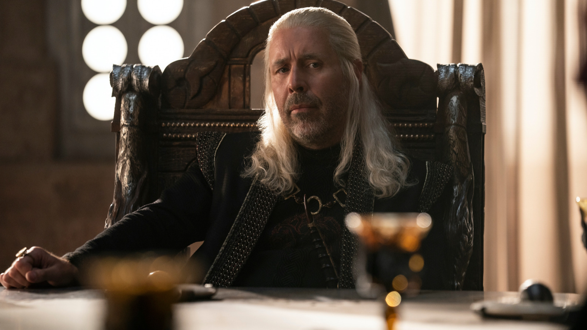 Viserys Targaryen I est assis à sa table. 