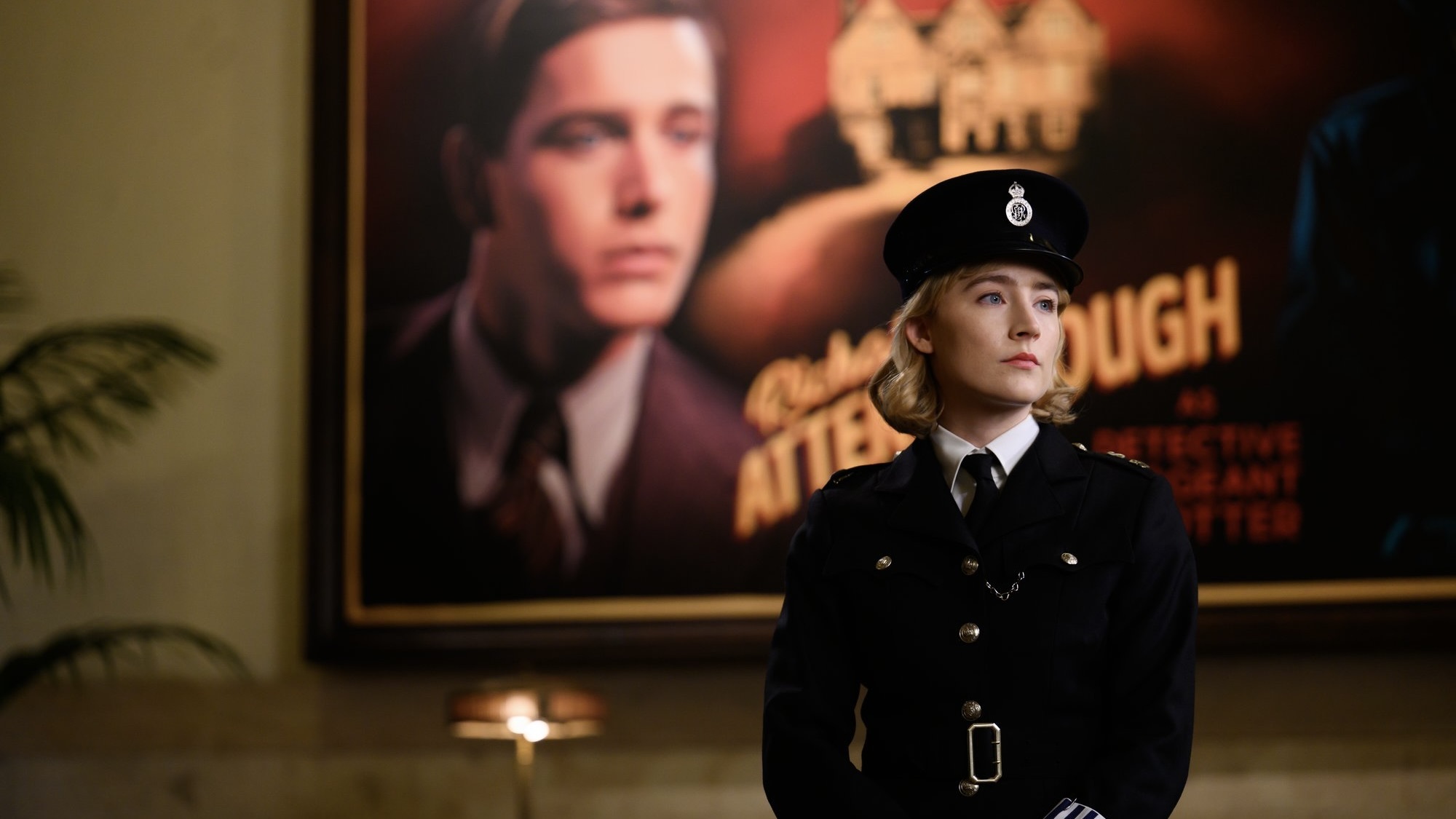 Une femme en uniforme d'agent de police se tient devant une affiche pour une production de 