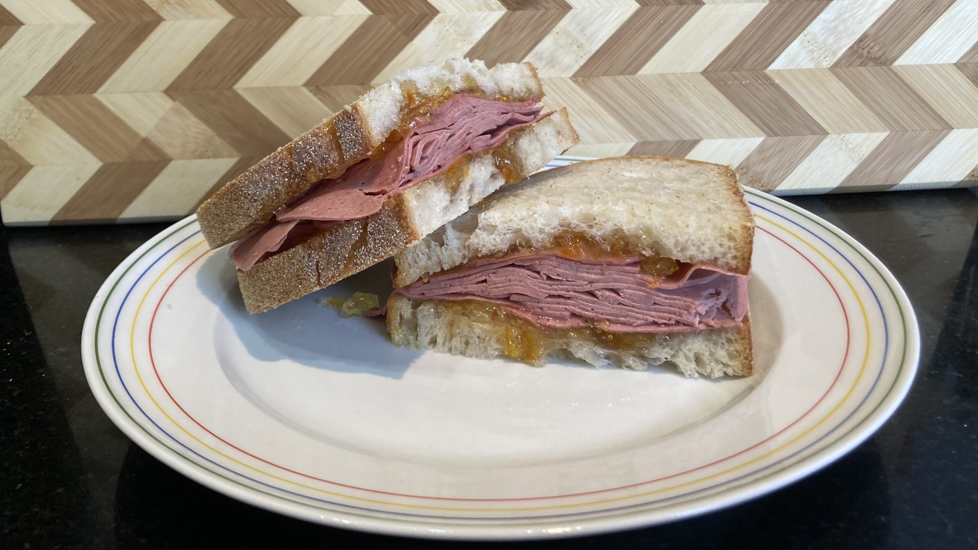 Une coupe transversale d'un sandwich à la saucisse de foie et à la marmelade sur une assiette.