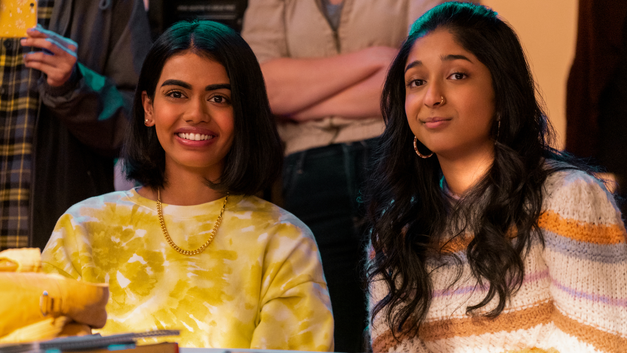 Deux filles sont assises en classe ensemble, souriantes.