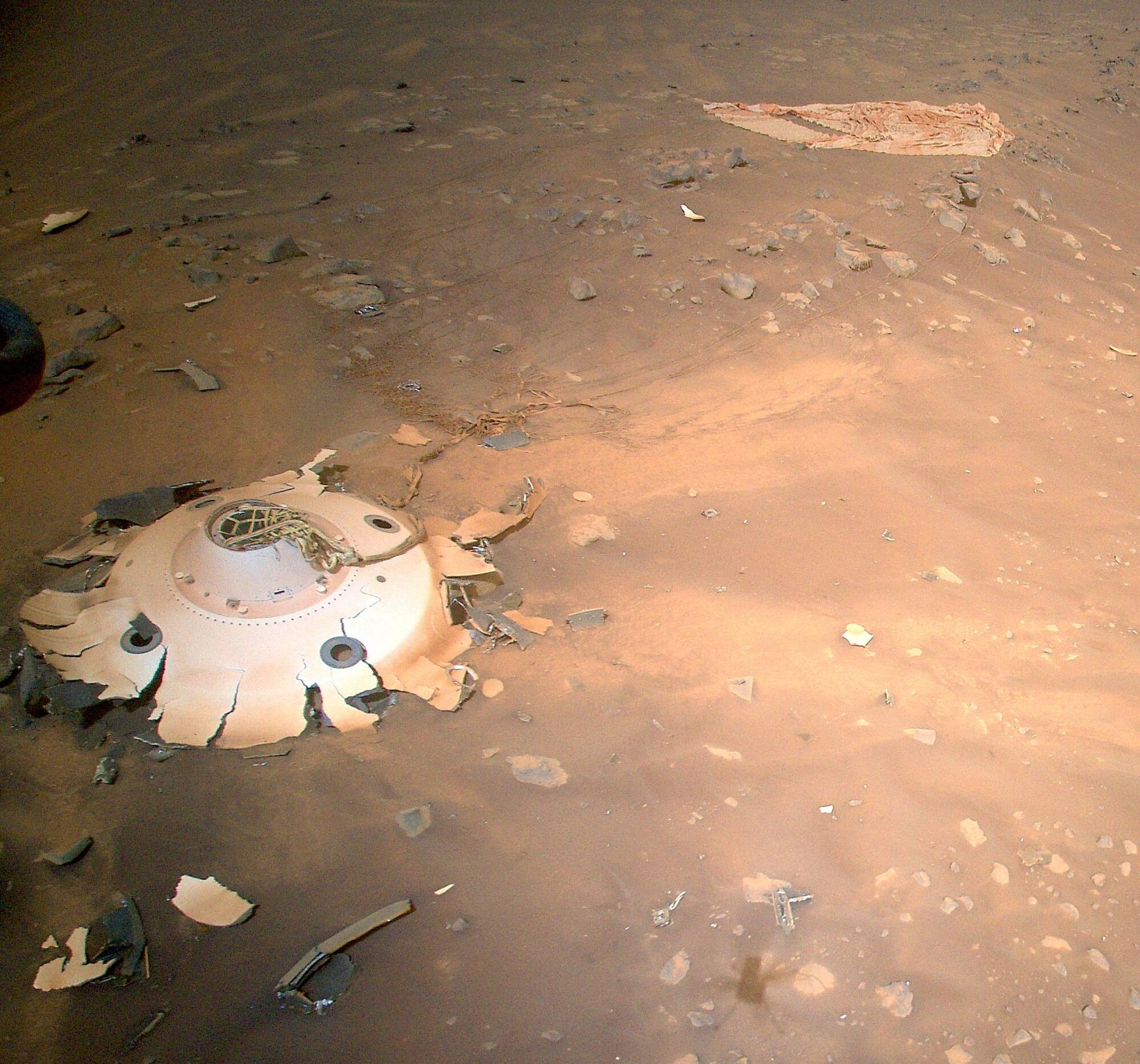 Un morceau de débris de métal blanc aux bords déchiquetés repose sur la surface poussiéreuse de Mars.