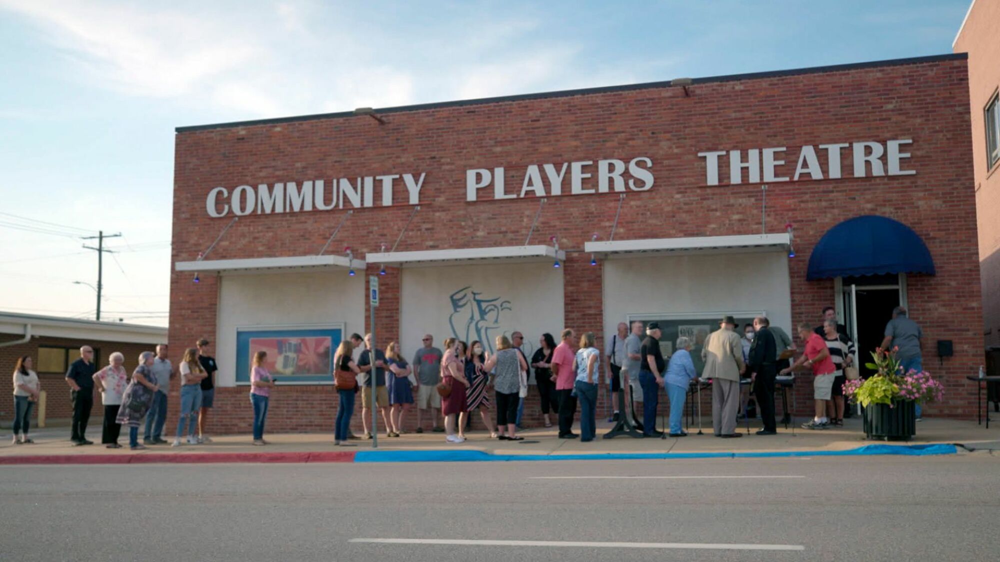 L'extérieur du Nebraska Community Players Theatre, avec une ligne de spectateurs qui s'enroulent autour du pâté de maisons. 