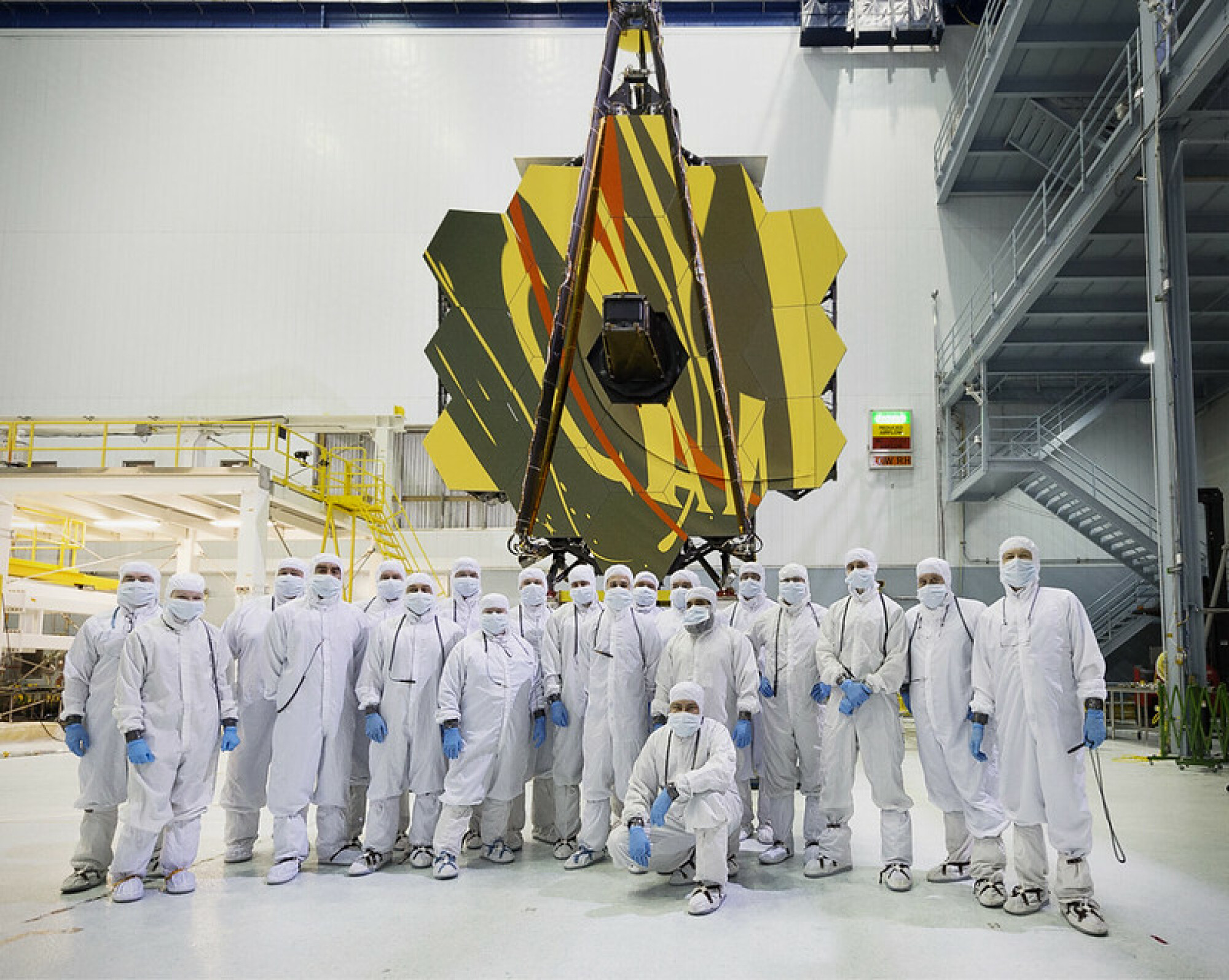 scientifiques debout devant le télescope spatial James Webb