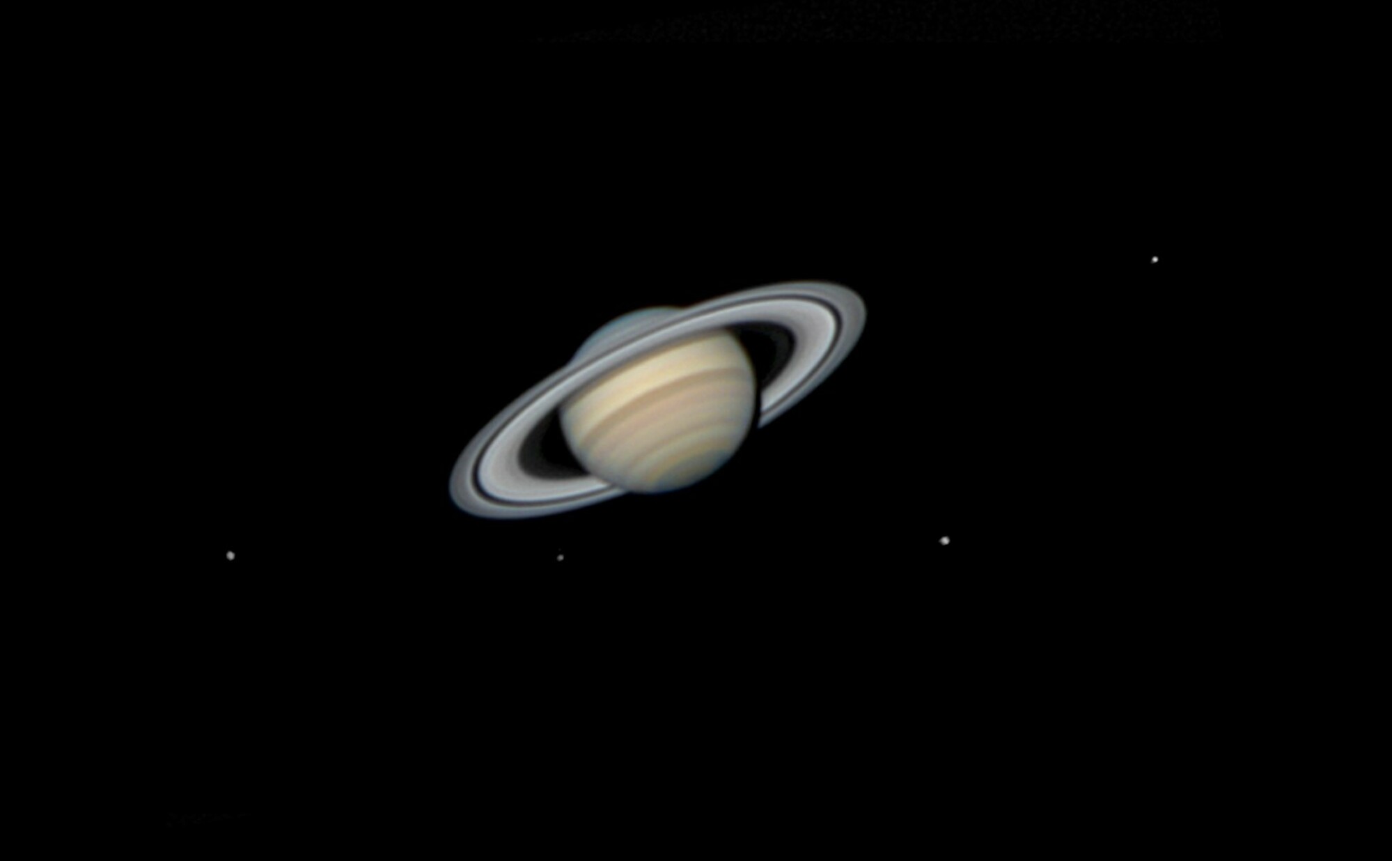 Les lunes de Saturne sont réparties presque symétriquement autour de la planète, équilibrant la composition de la photographie. 