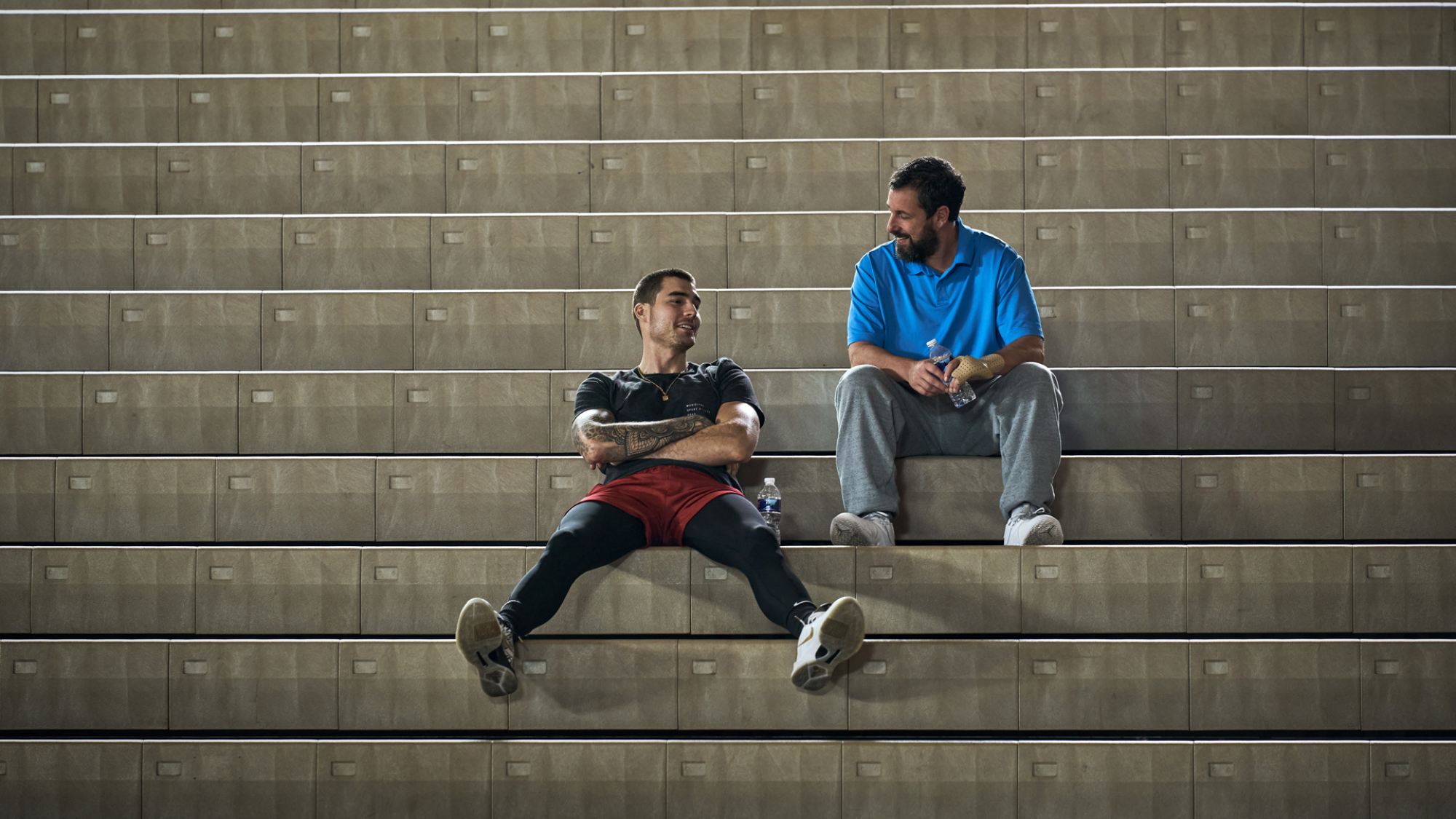 Deux hommes sont assis dans une tribune de basket.