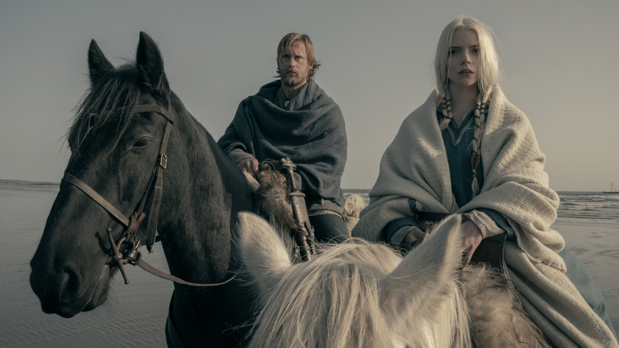 Deux personnes en robe viking sont assises sur des chevaux.