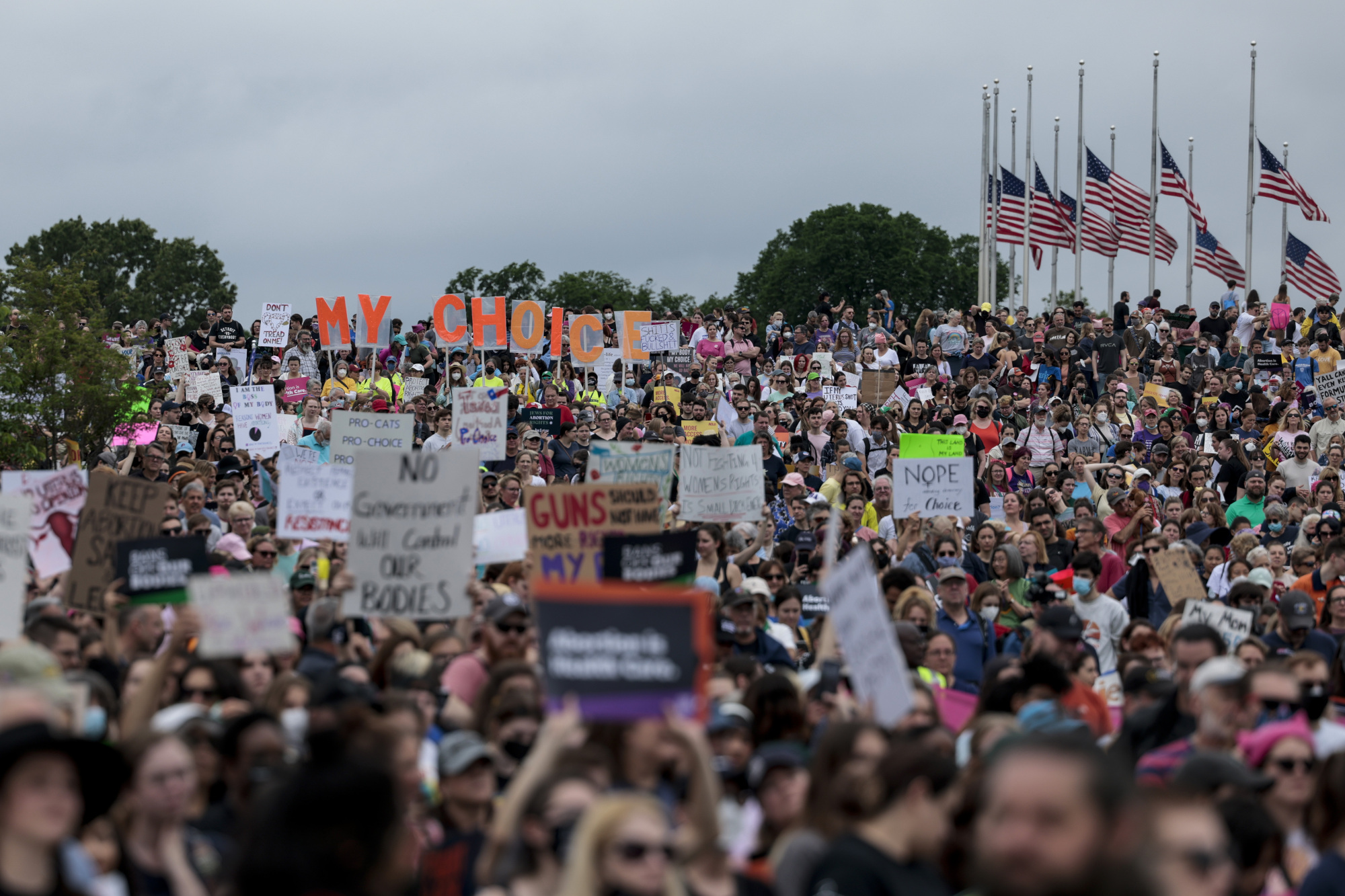 Un grand groupe de personnes marche vers le Washington Monument portant des pancartes.