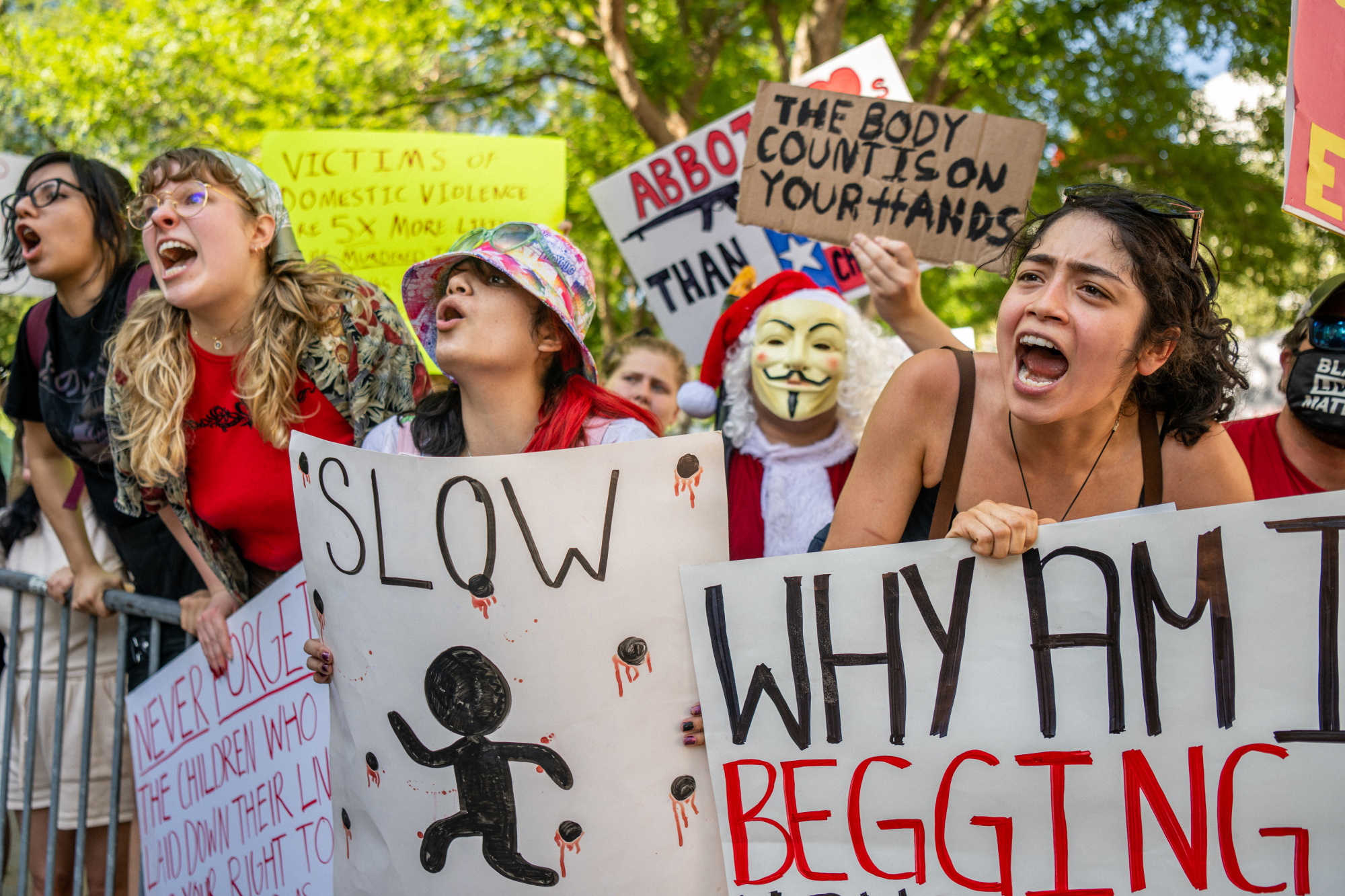 Un groupe de manifestants brandissant diverses pancartes crie après les participants à la convention de la NRA.