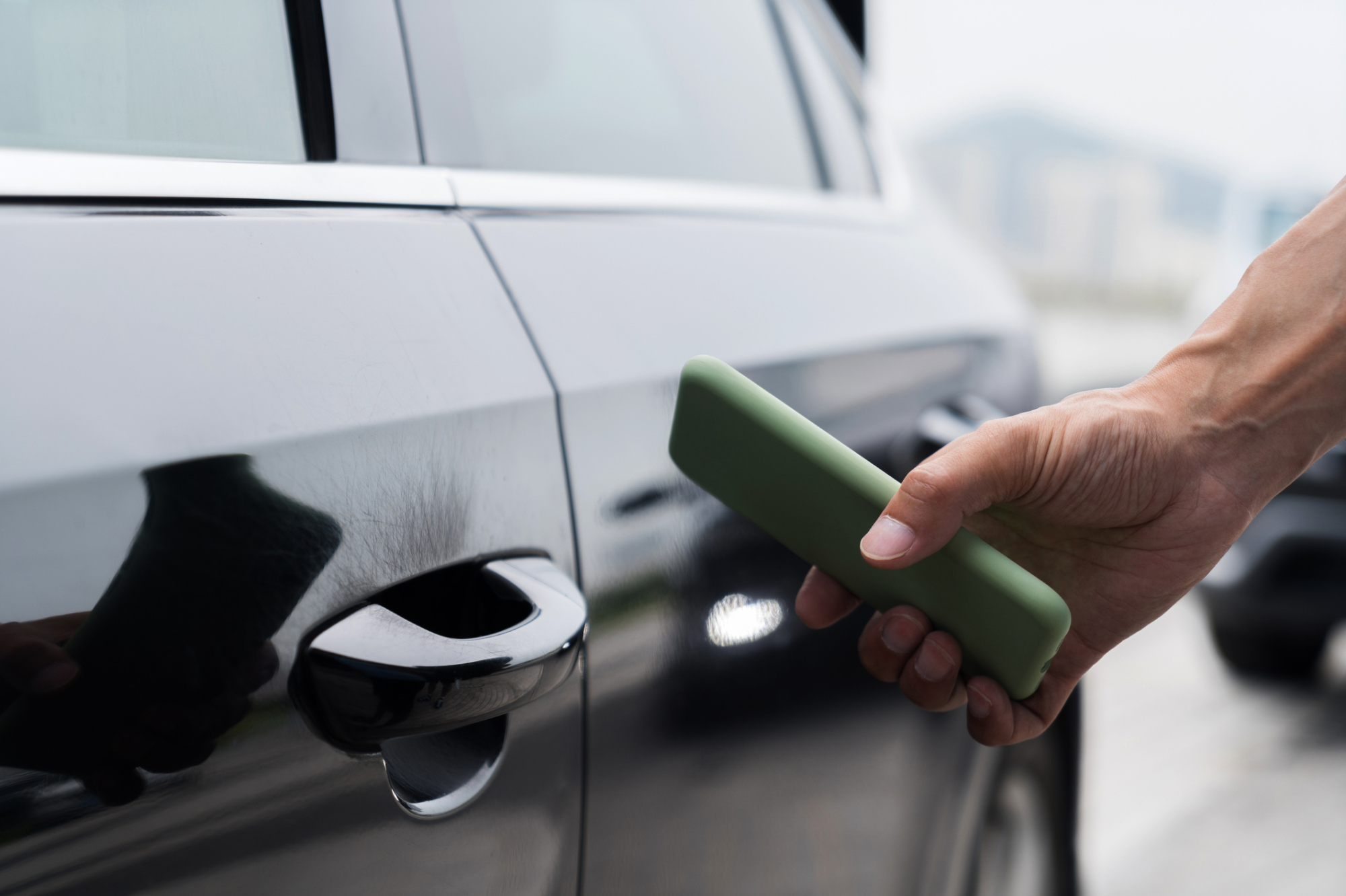 Voiture noire avec la main de quelqu'un à proximité tenant un smartphone vert.