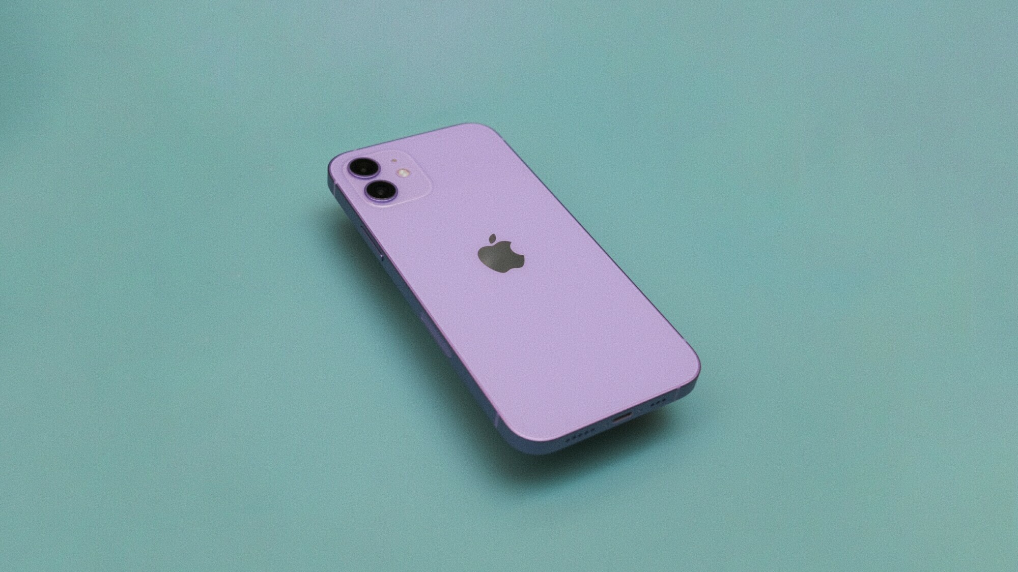 L'iPhone 12 violet clair repose face vers le bas sur une surface verte.