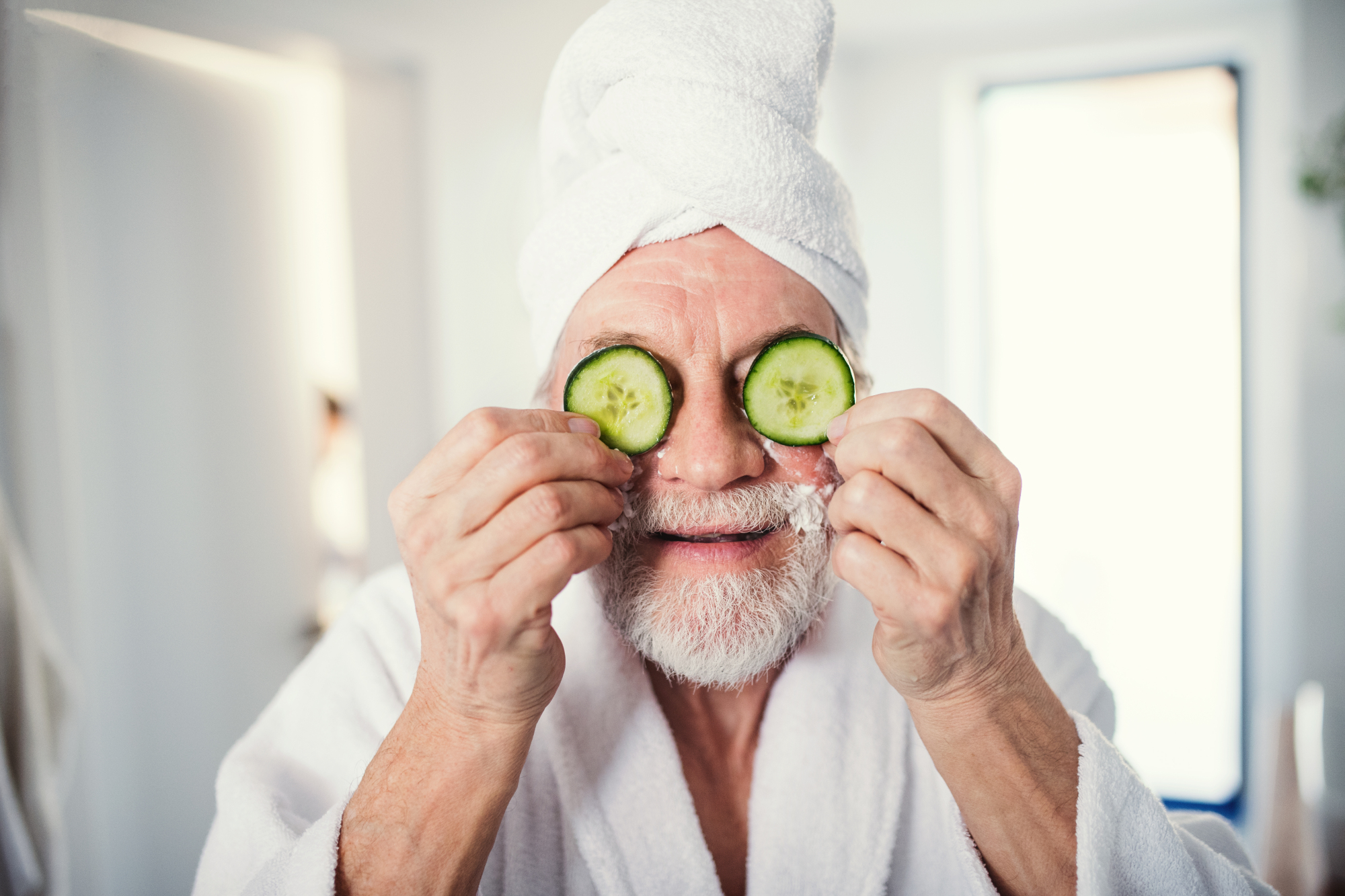 un homme d'âge moyen tenant des concombres sur ses yeux