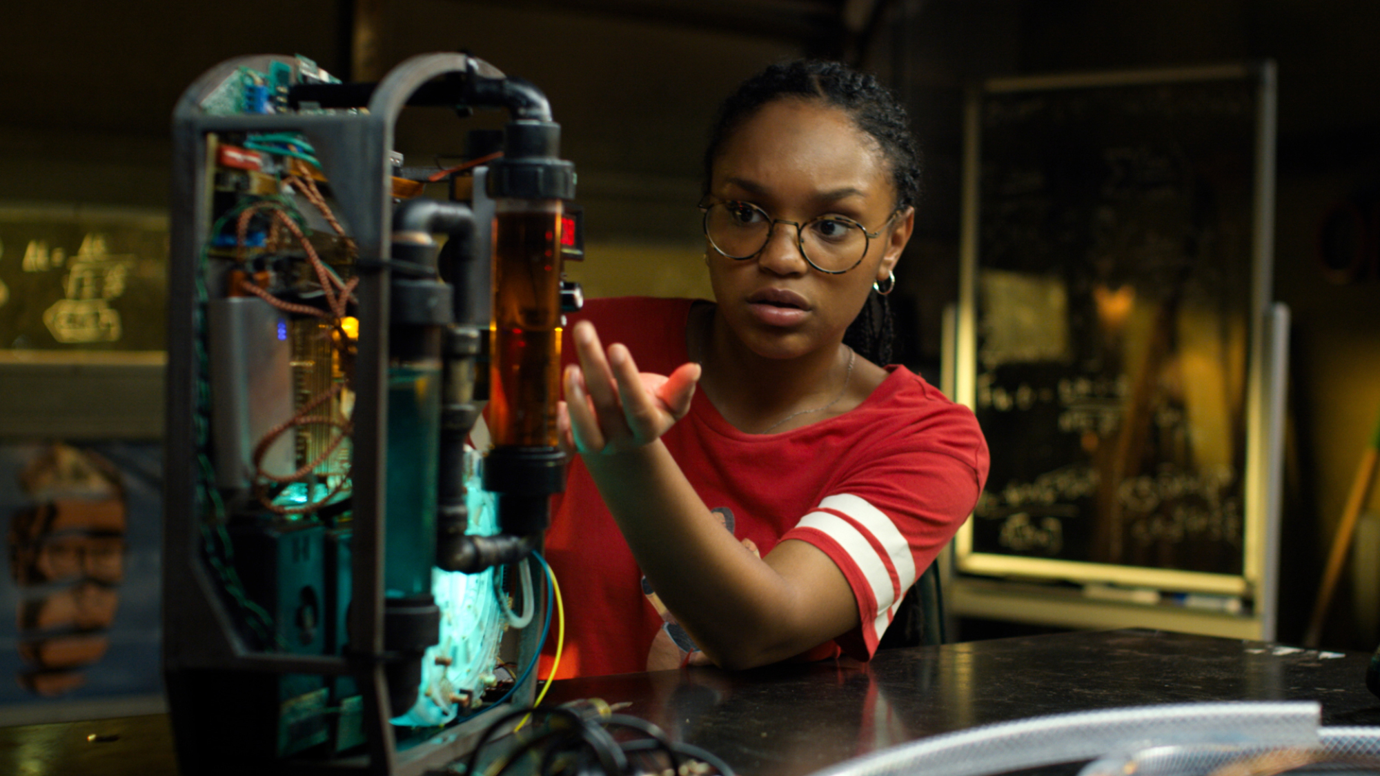 Une fille travaille sur un projet électronique dans un garage. 