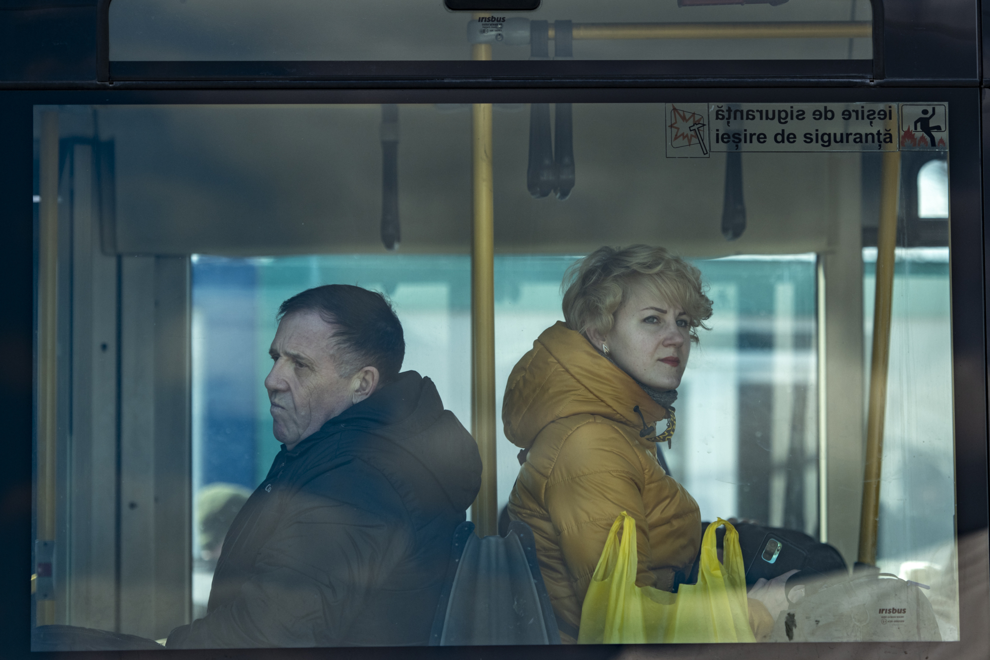 Un homme et une femme sont assis dos à dos dans les transports en commun. 