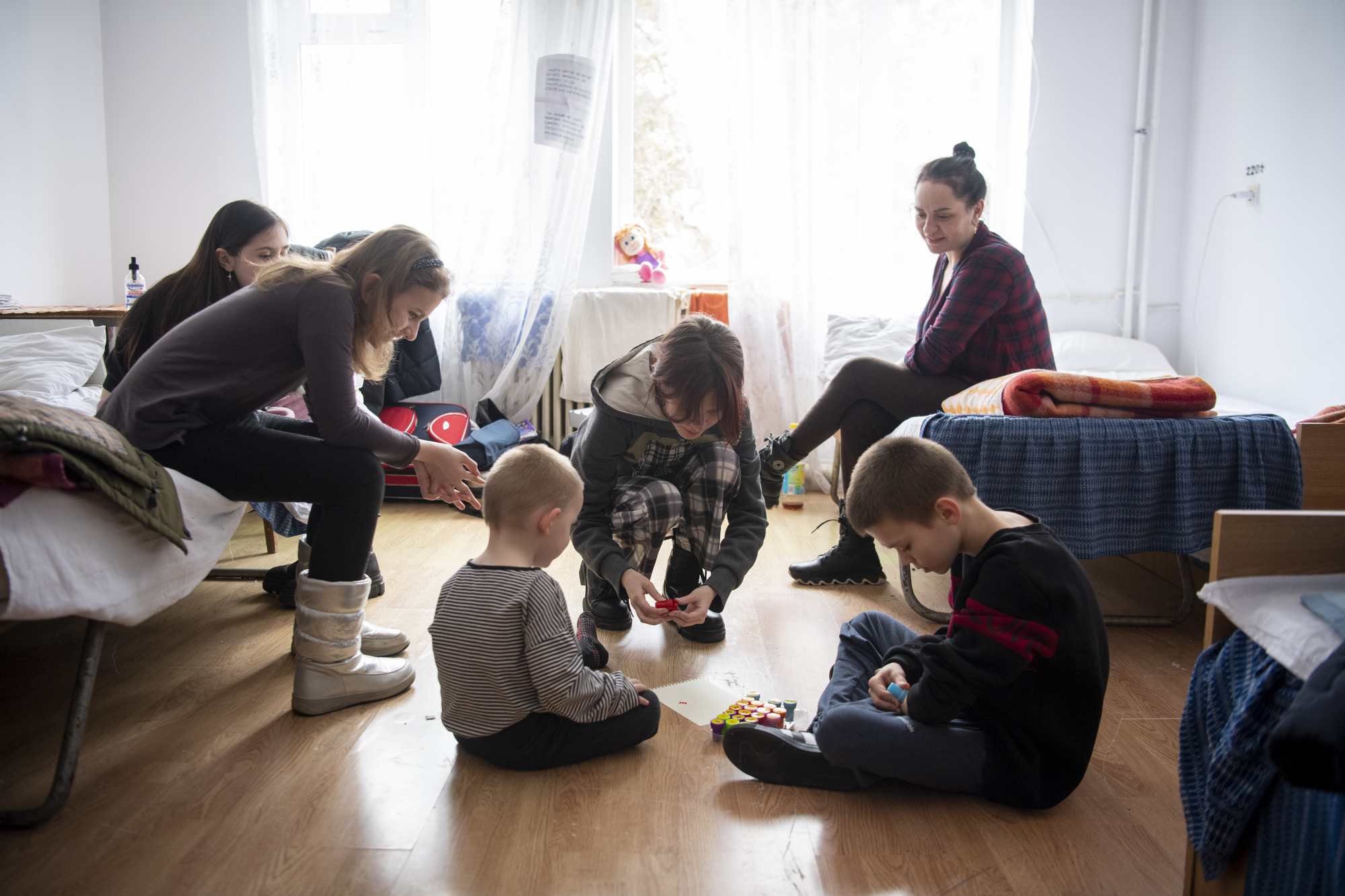 Les femmes et les enfants sont assis sur un sol dans un appartement.