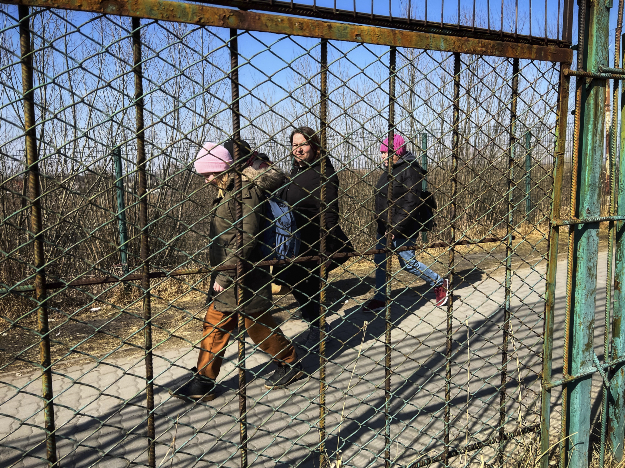 Les gens marchant dans la rue par un mur clôturé.