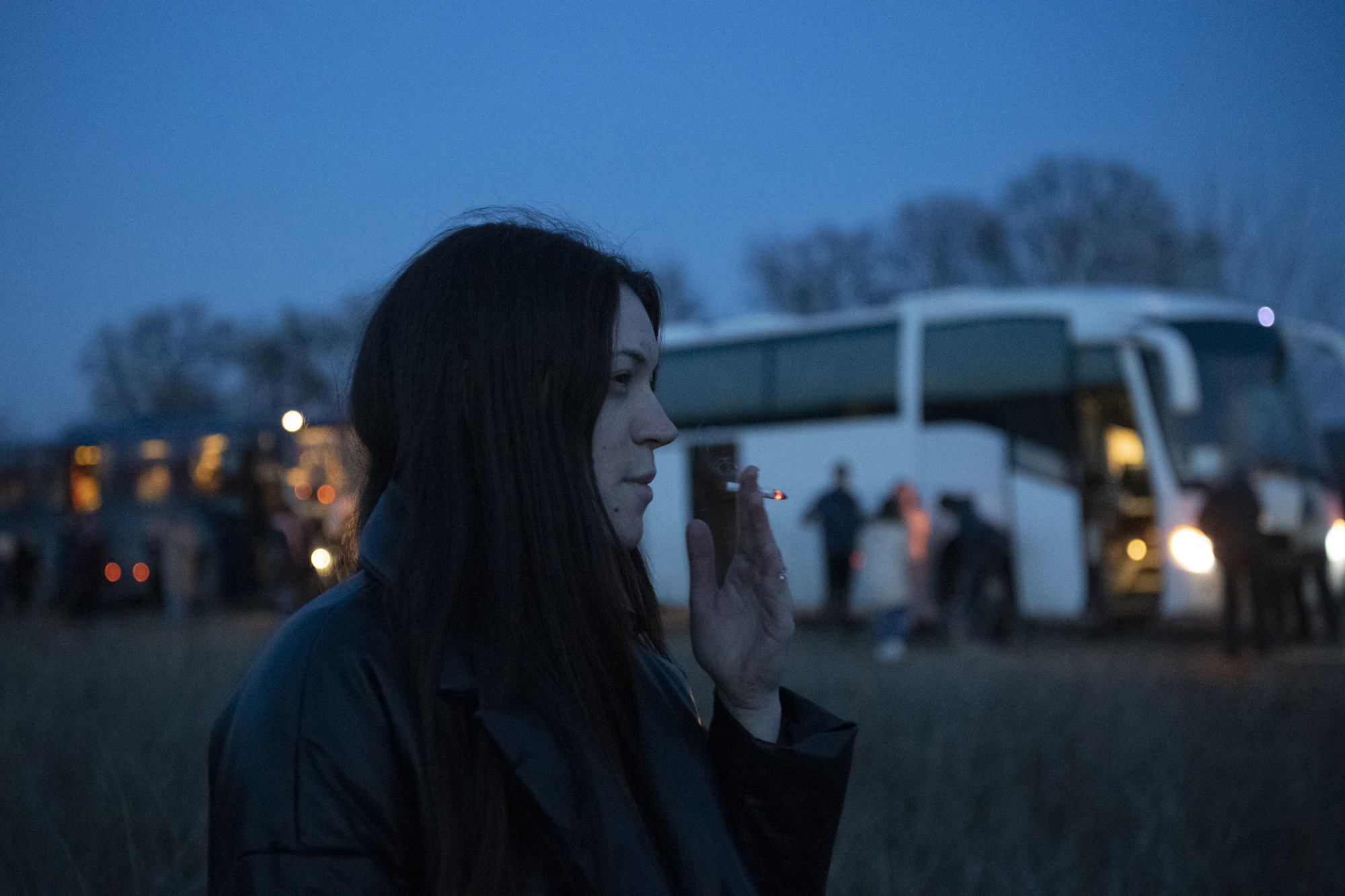 Une femme qui fume une cigarette près d'un bus.