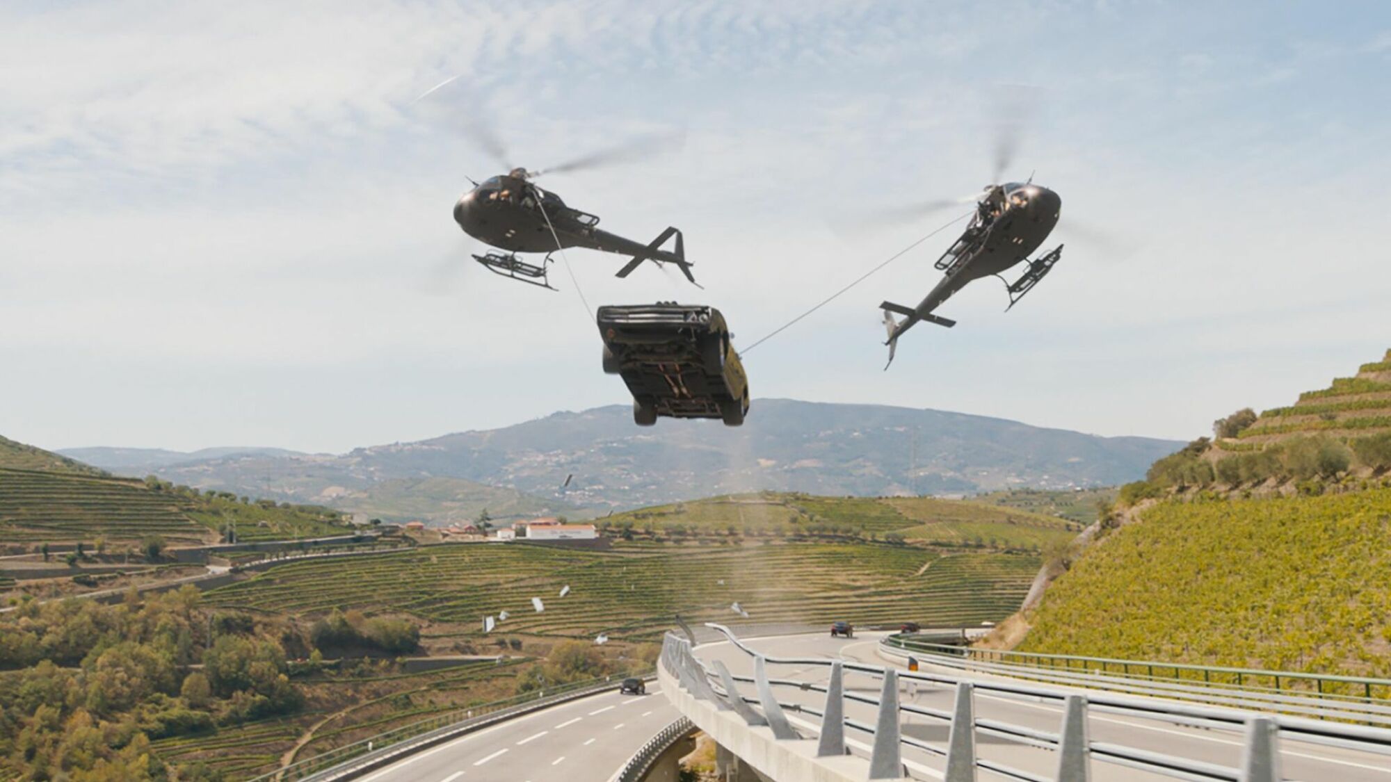 Deux hélicoptères traînent une voiture dans les airs 