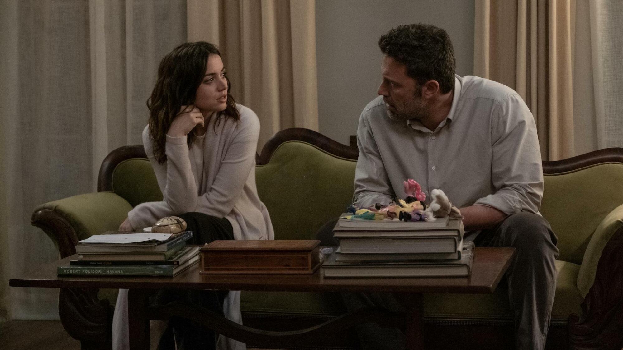 Ana De Armas et Ben Affleck sont assis sur un canapé et se regardent.