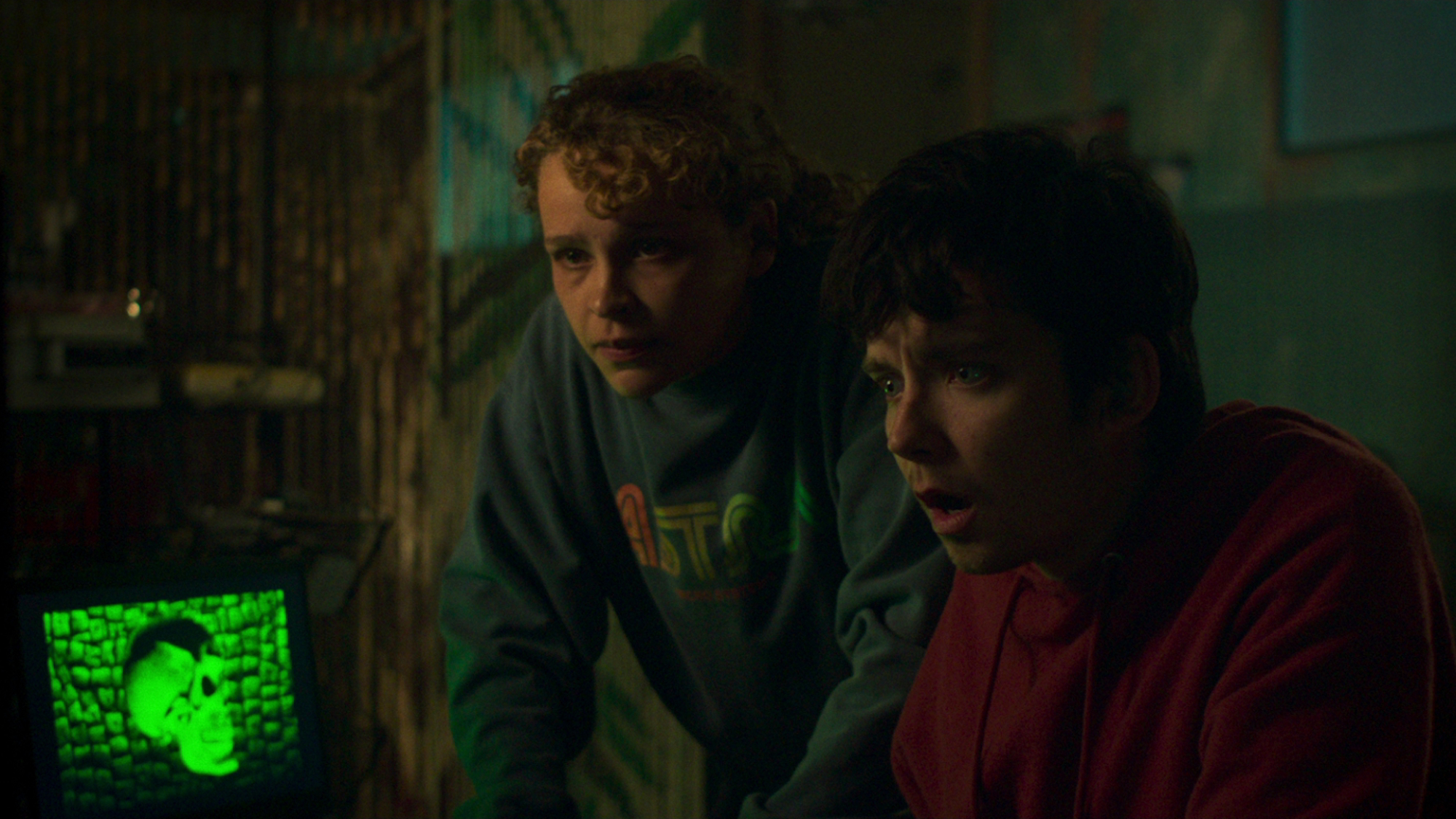 Deux personnes regardent fixement un écran d'ordinateur : Iola Evans dans le rôle de Kayla et Asa Butterfield dans le rôle d'Issac dans 